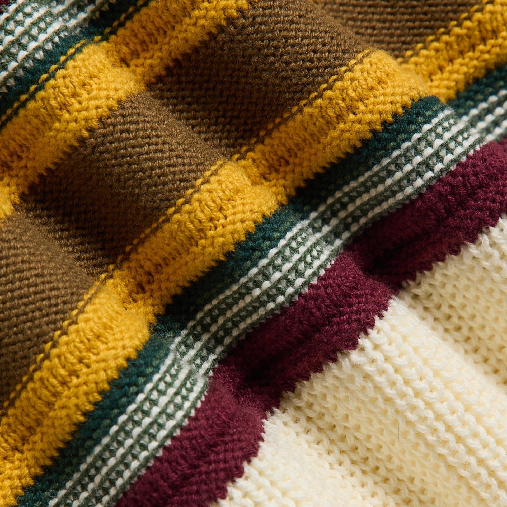 Close-up of the Kith Baby Chunky Knit Rugby Shirt's chunky knit striped fabric in maroon, gold and green
