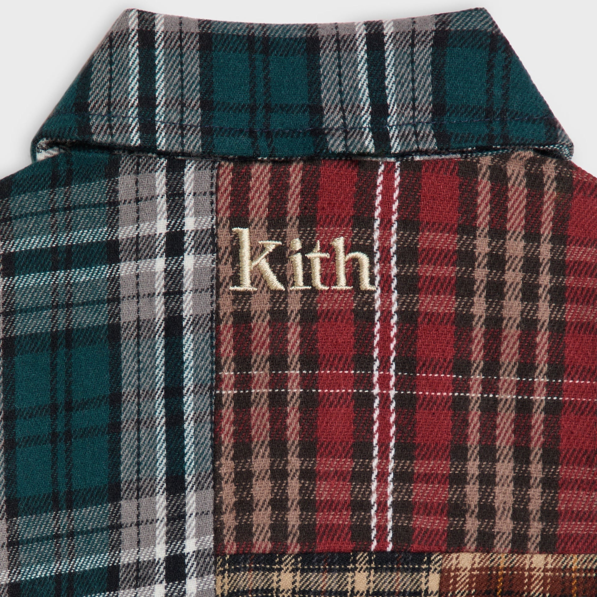 Close-up of the Kith Baby Patchwork Plaid Apollo Shirt's back yoke with gold Kith embroidery on mixed plaid panels