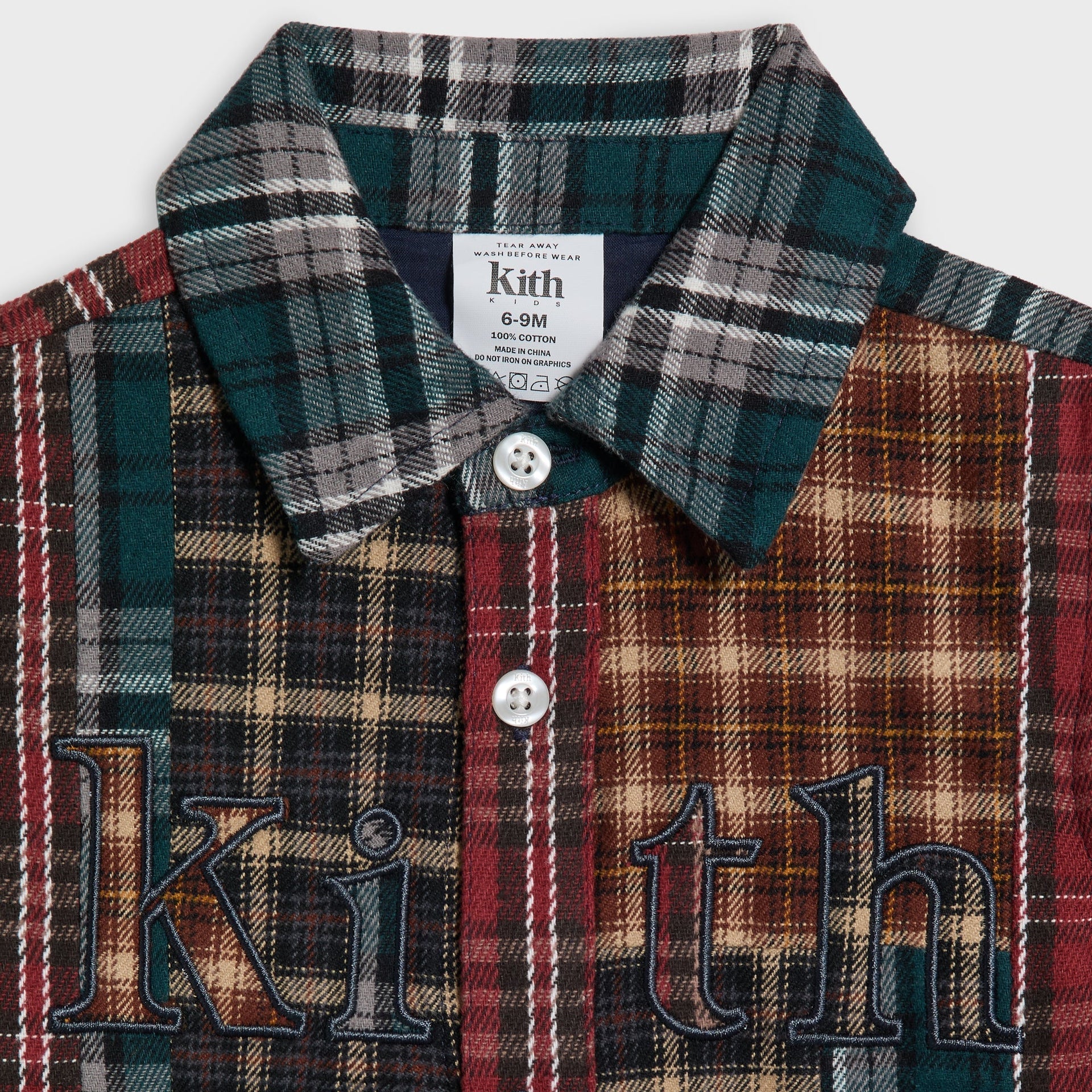 Close-up of the Kith Baby Patchwork Plaid Apollo Shirt's collar and button placket showing embroidered Kith lettering
