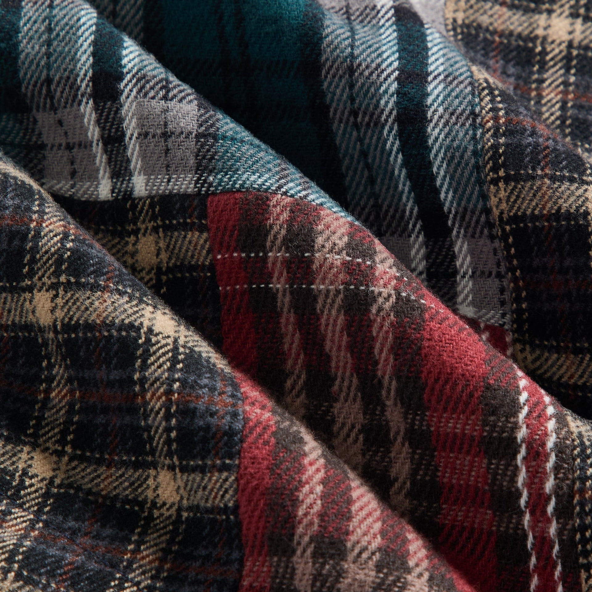 Close-up of the Kith Baby Patchwork Plaid Apollo Shirt's mixed plaid flannel fabric in green, red, black and tan
