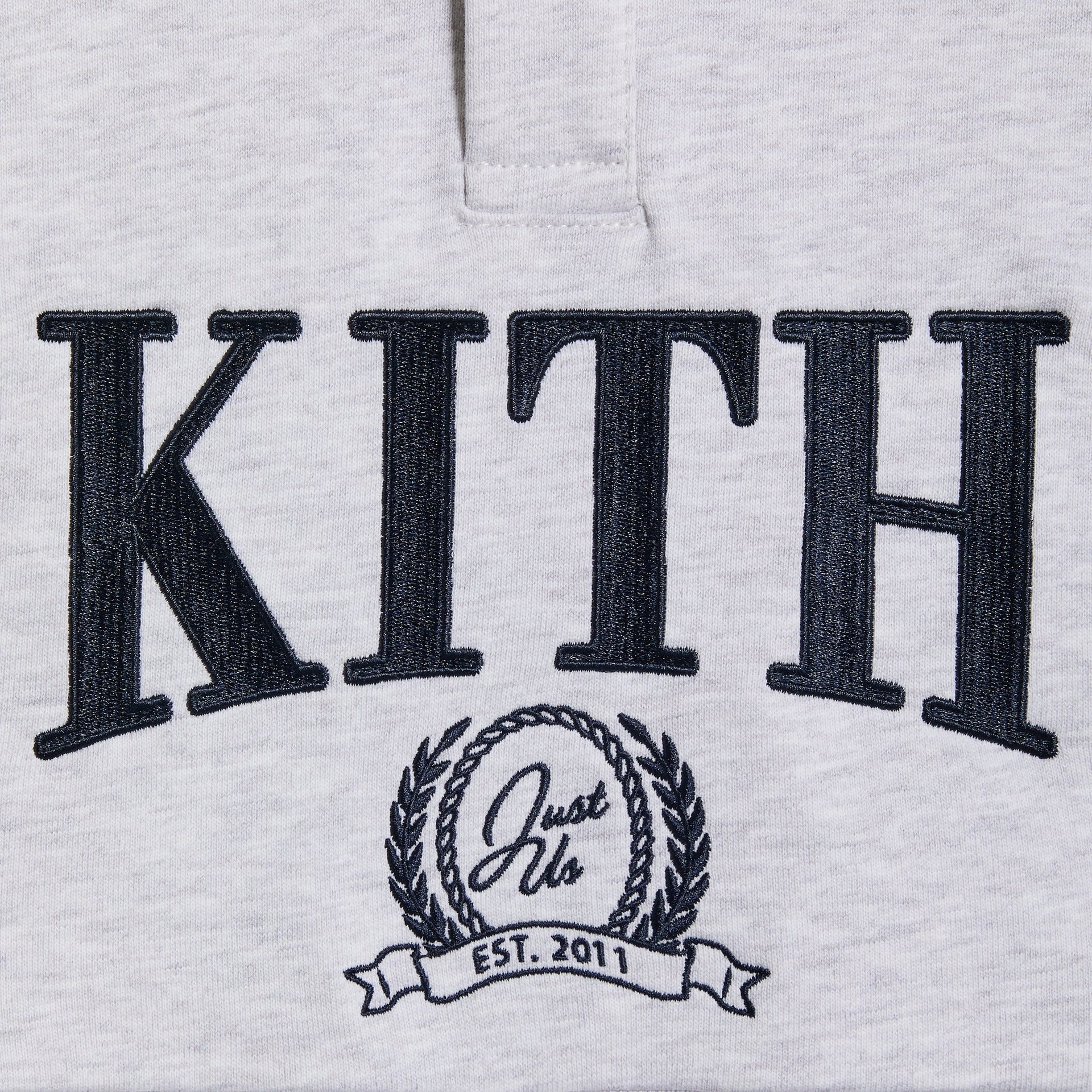 Close-up of the Kith Baby Collegiate Snap Hunter Crewneck's embroidered Kith and Just Us Est. 2011 crest logo