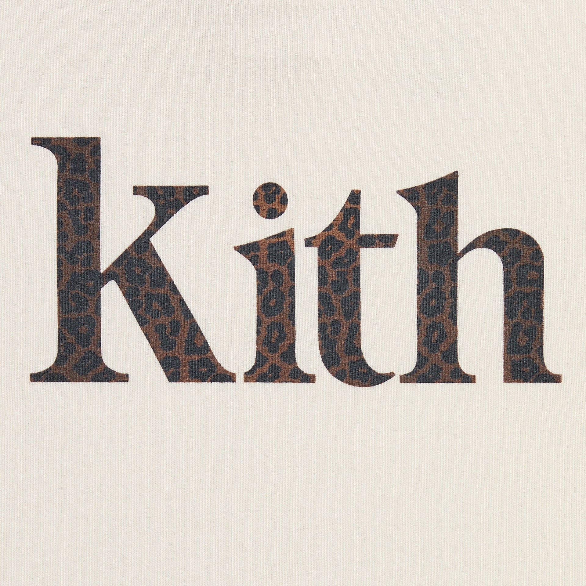 Close-up of the Kith Baby Leopard Kith Serif Leonard Tee's leopard-print Kith serif logo on cream jersey
