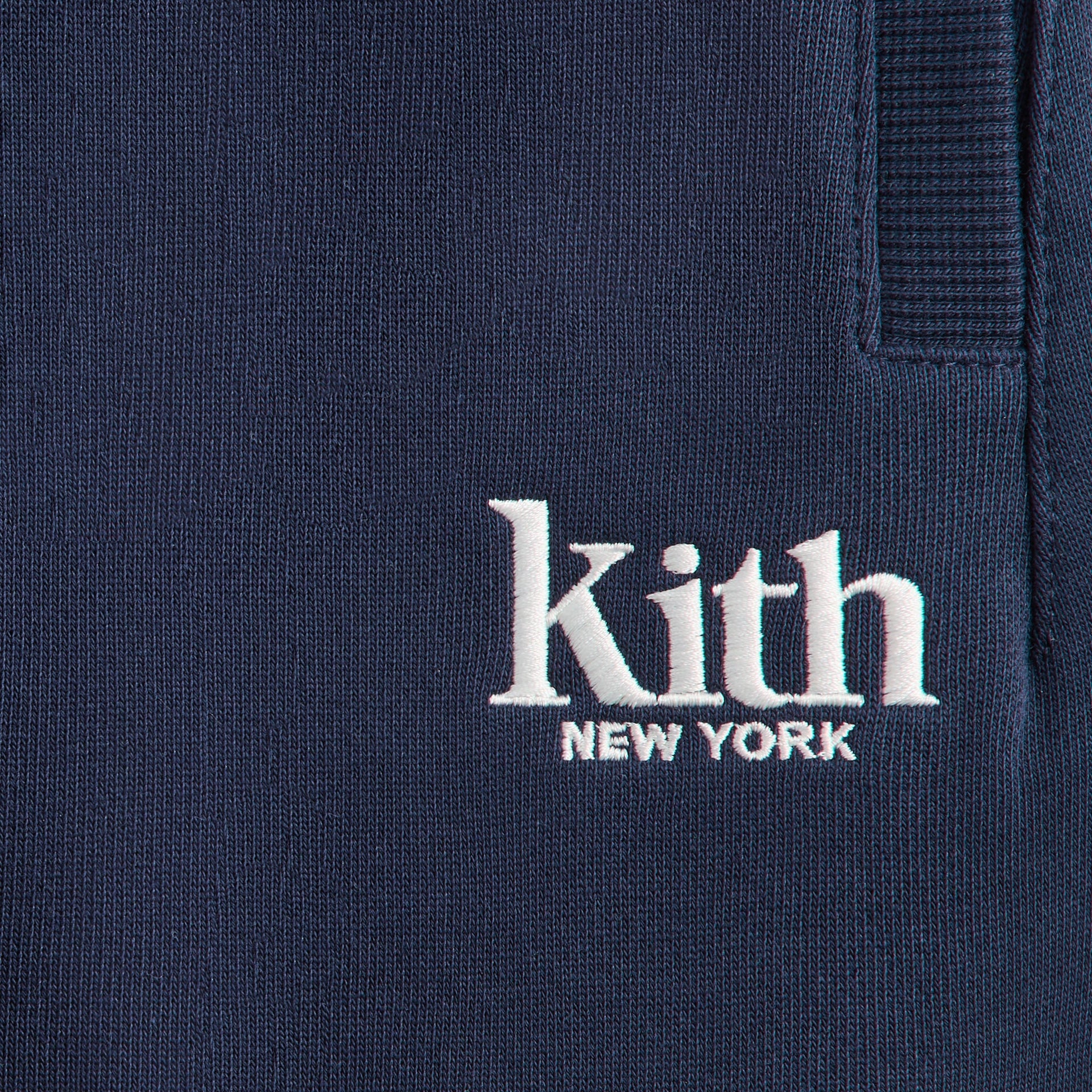 Kith Baby Williams II Pant, close-up of white Kith New York embroidery on navy fleece