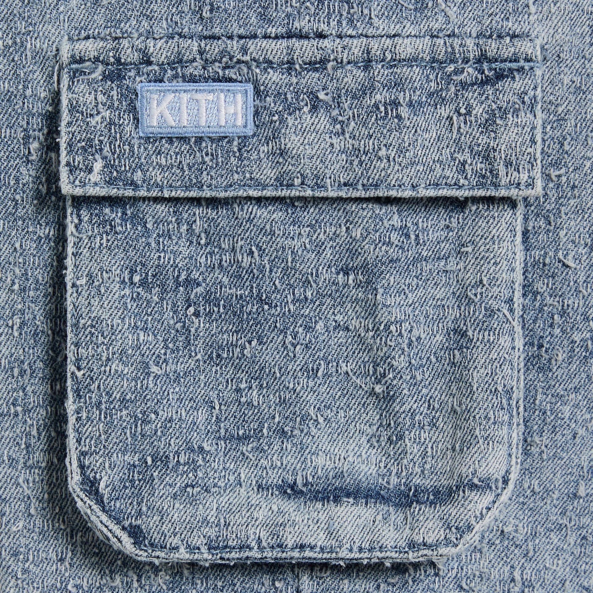 Close-up of the Kith Baby Textured Denim Chauncey Pant's cargo pocket with woven Kith patch label