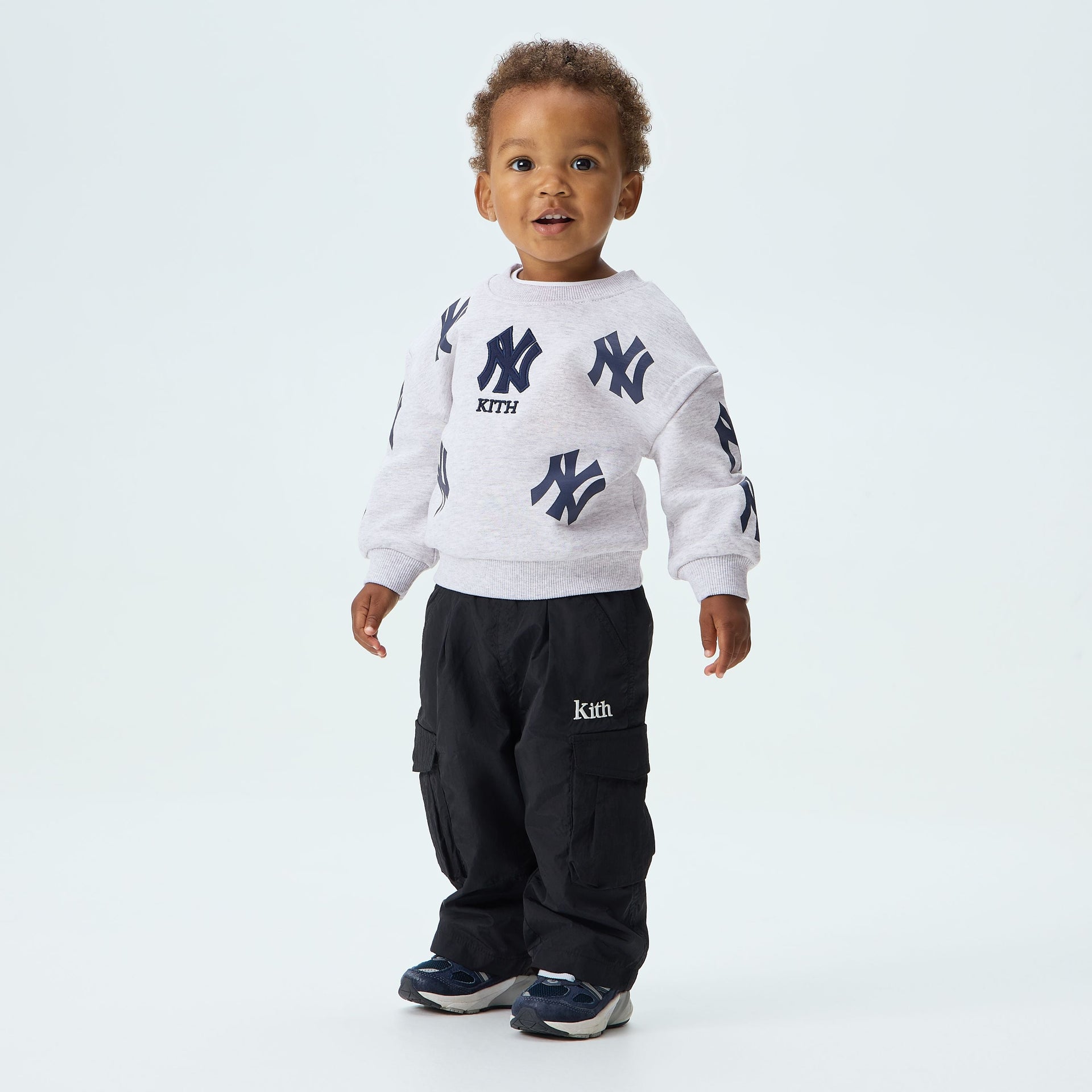 Kith Baby for the New York Yankees Nelson Crewneck in Light Heather Grey, worn by a baby model with black cargo pants, front view