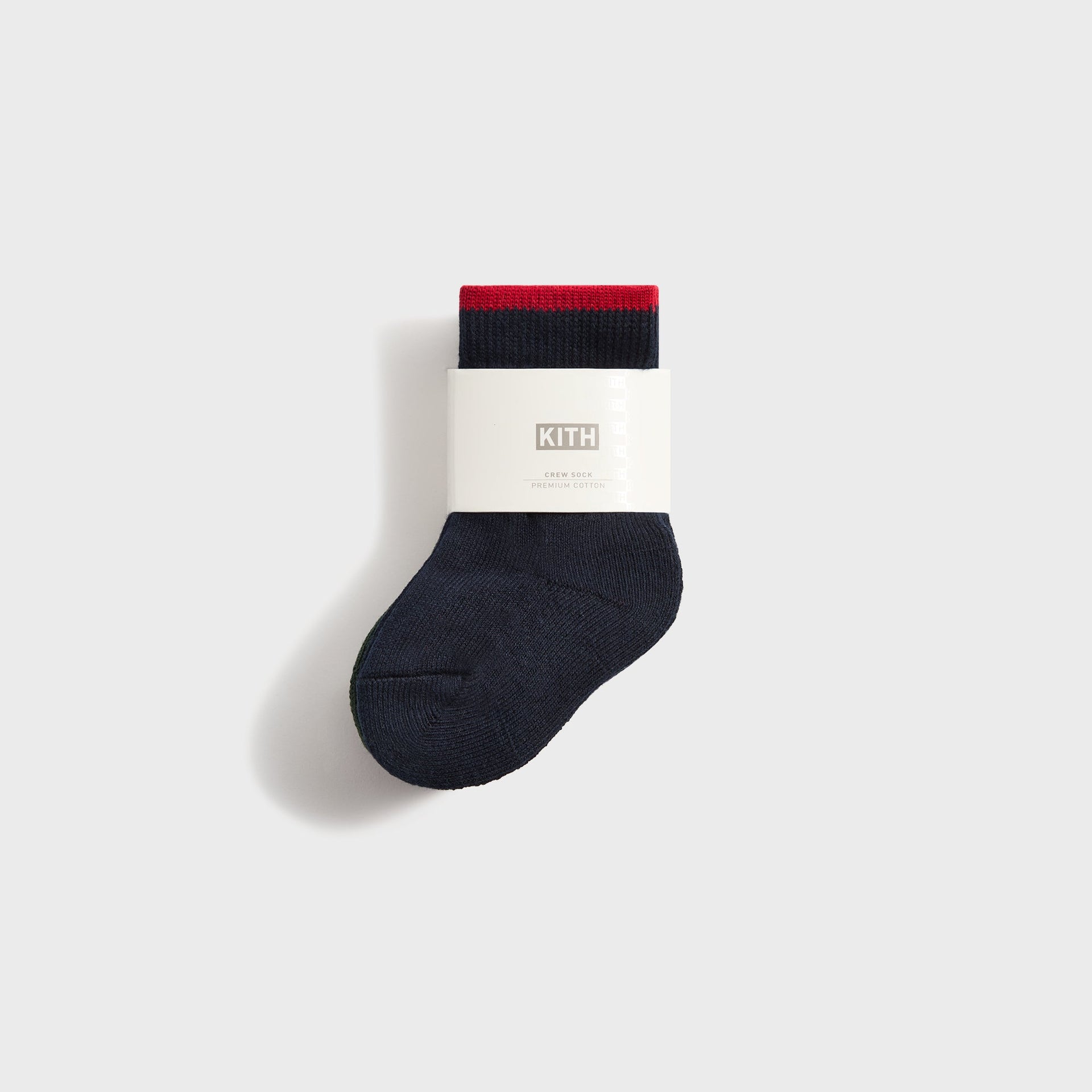 Navy Kith Baby NY crew sock with red stripe cuff, folded in a KITH premium cotton paper band