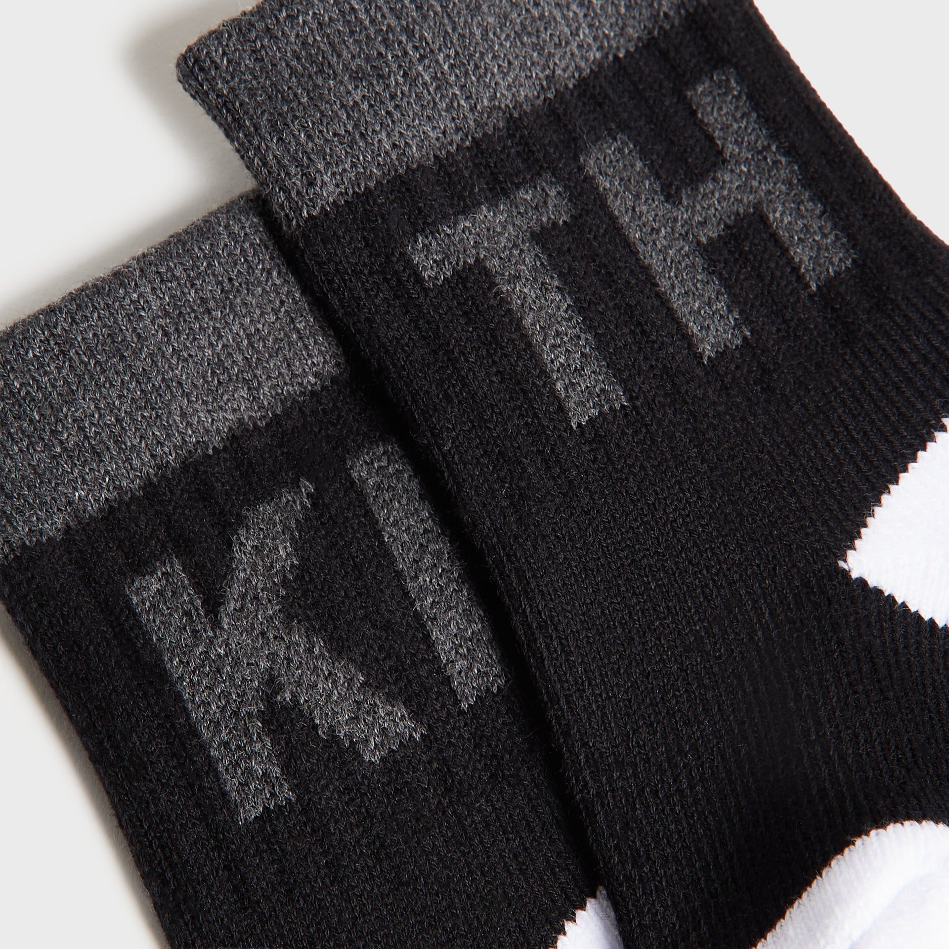 Kith Baby Color-Blocked Crew Socks, close-up of black and charcoal grey cuffs with tonal KITH jacquard lettering