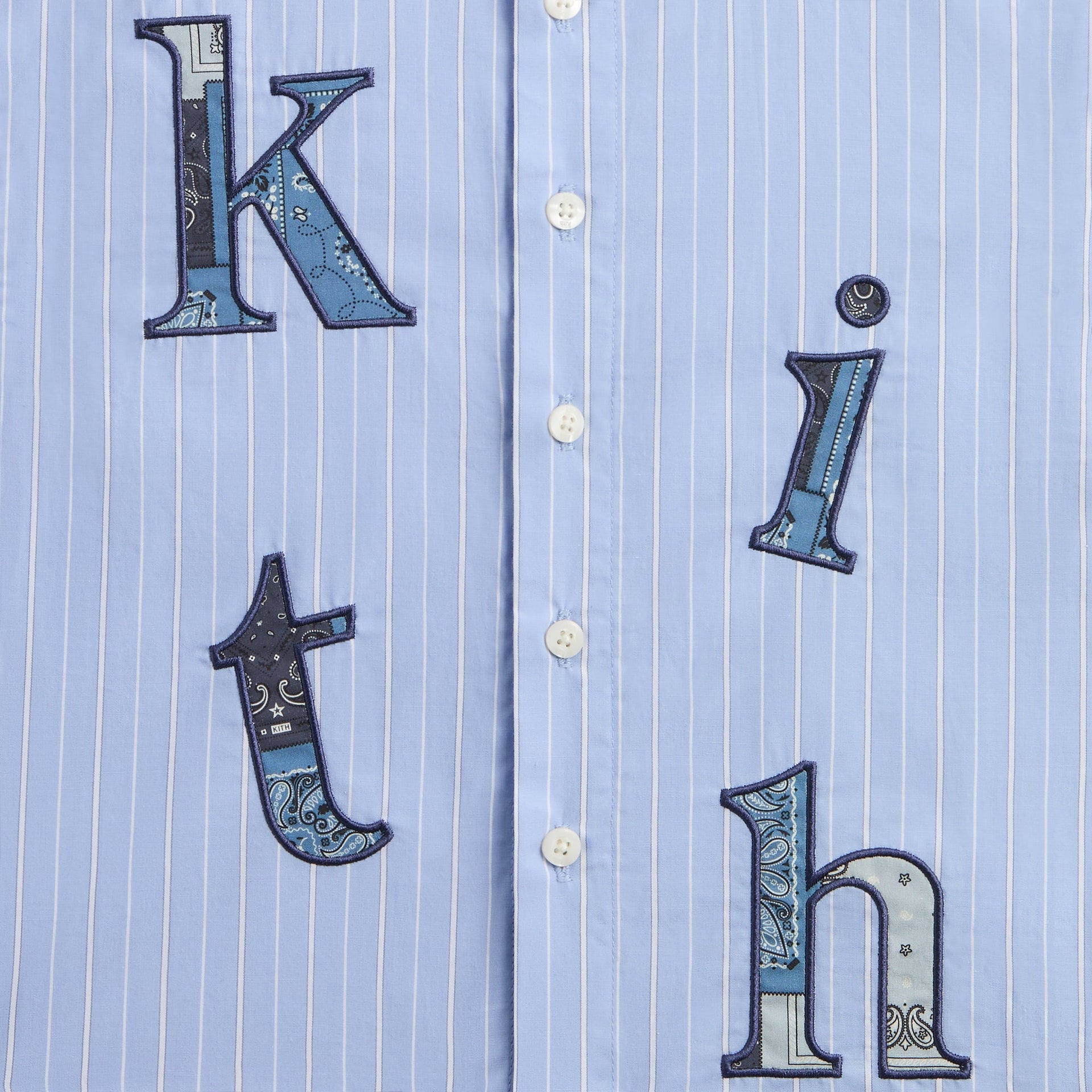 Close-up of the blue bandana paisley applique kith letters on the pinstripe Berkeley shirt