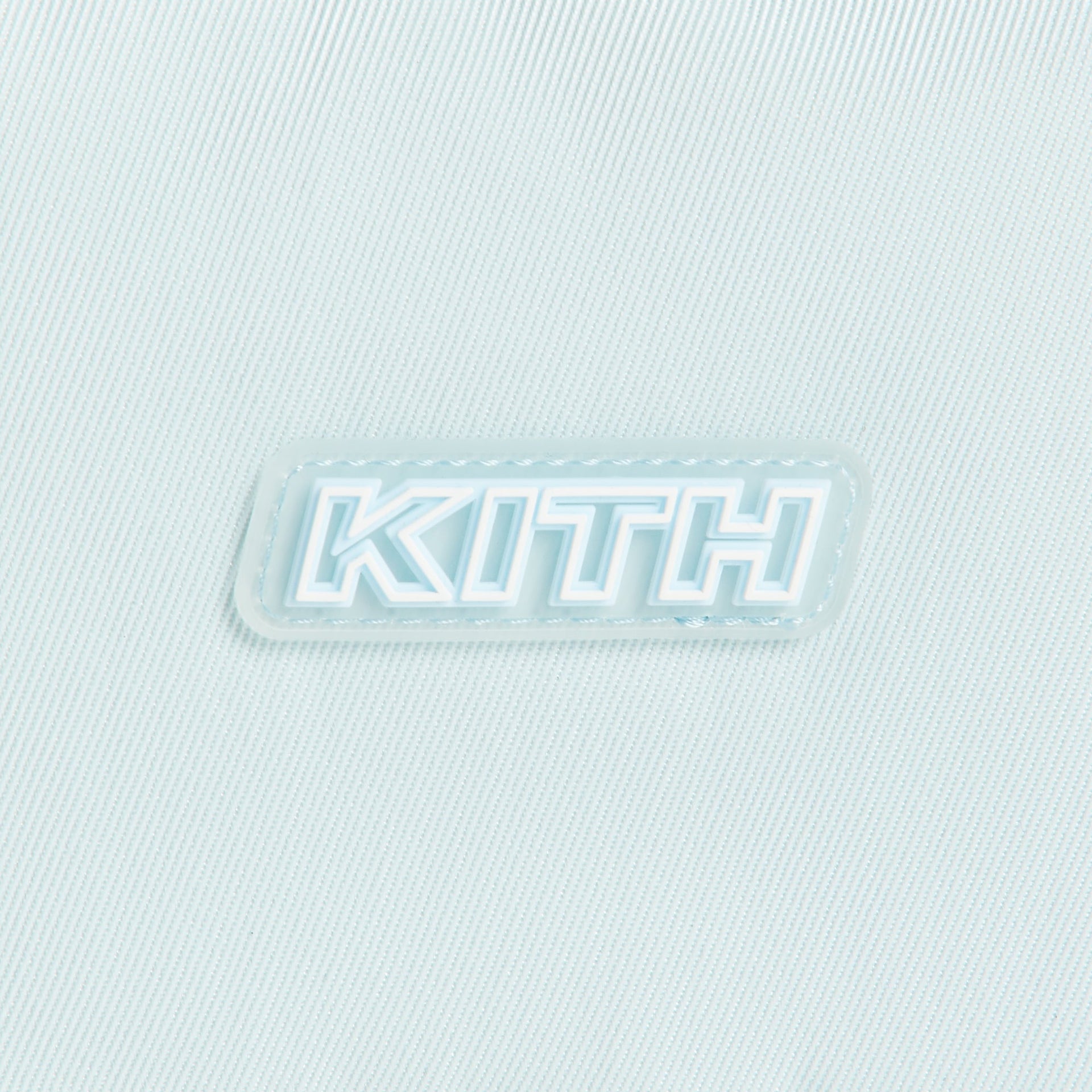 Close-up of the raised KITH rubber logo patch on light blue twill of the Kith Kids Active belt bag