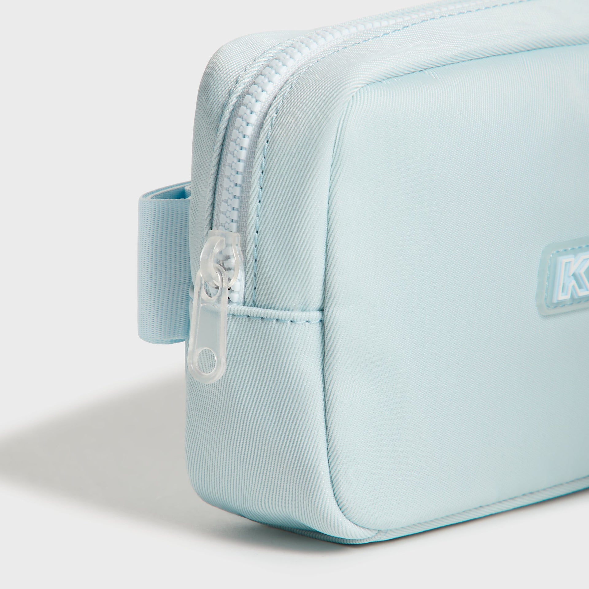 Side detail of the Kith Kids Active belt bag in light blue showing clear zipper pull and belt loop