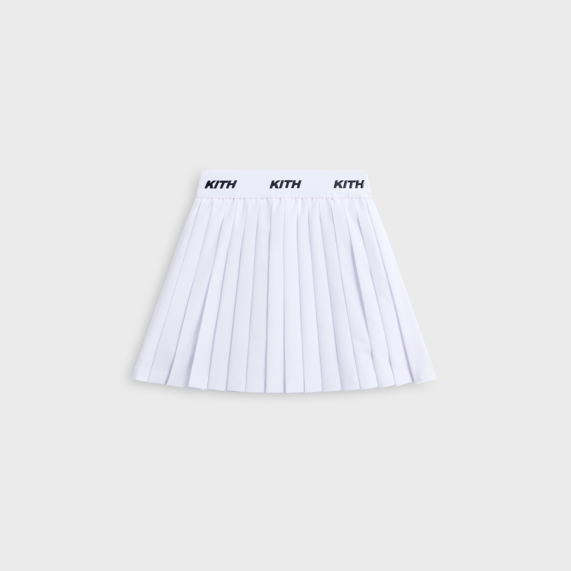 Kith Kids Amaya Tennis Mini Skort in white, flat lay front view with pleats and KITH logo waistband