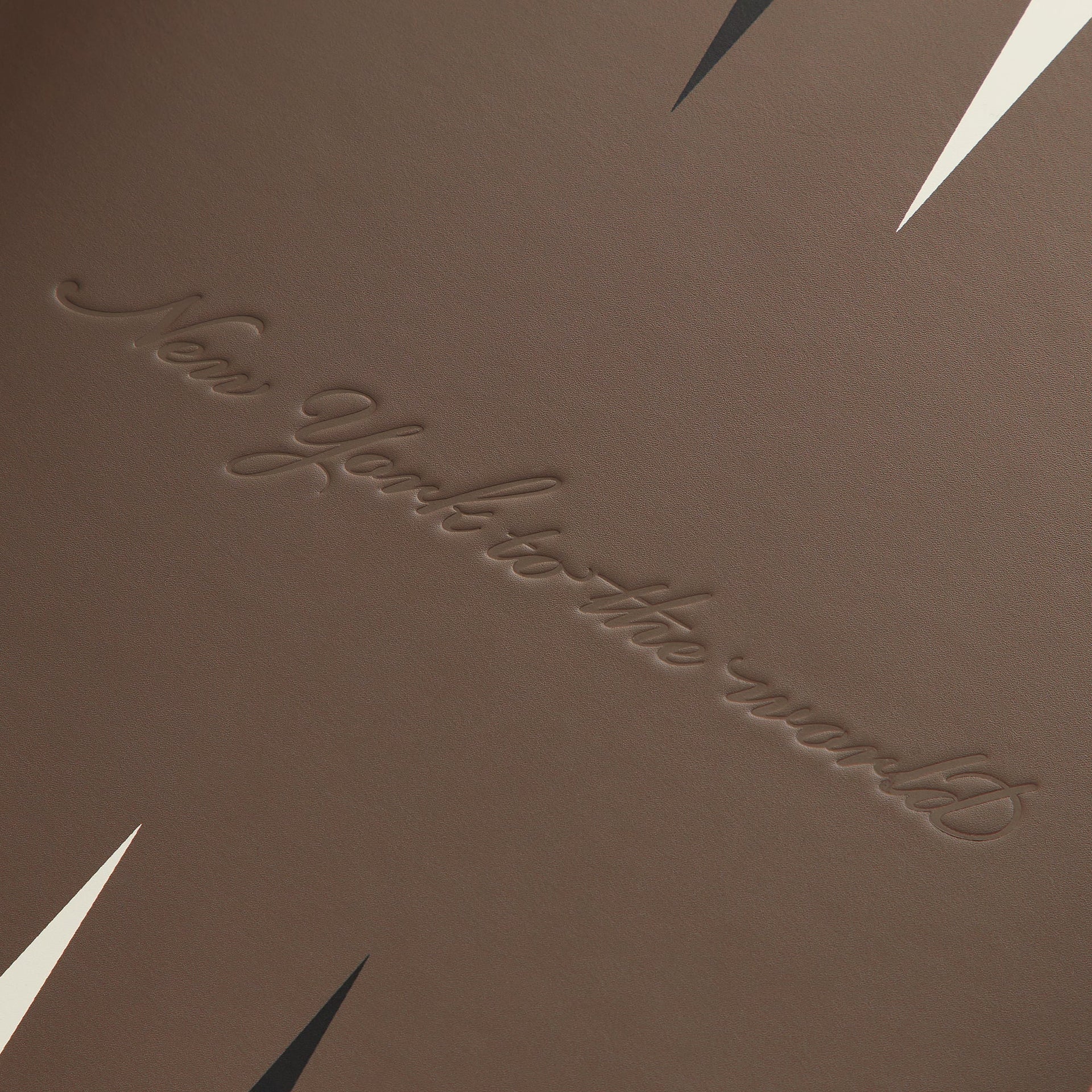 Close-up of the debossed New York to the World script between the black and cream playing triangles