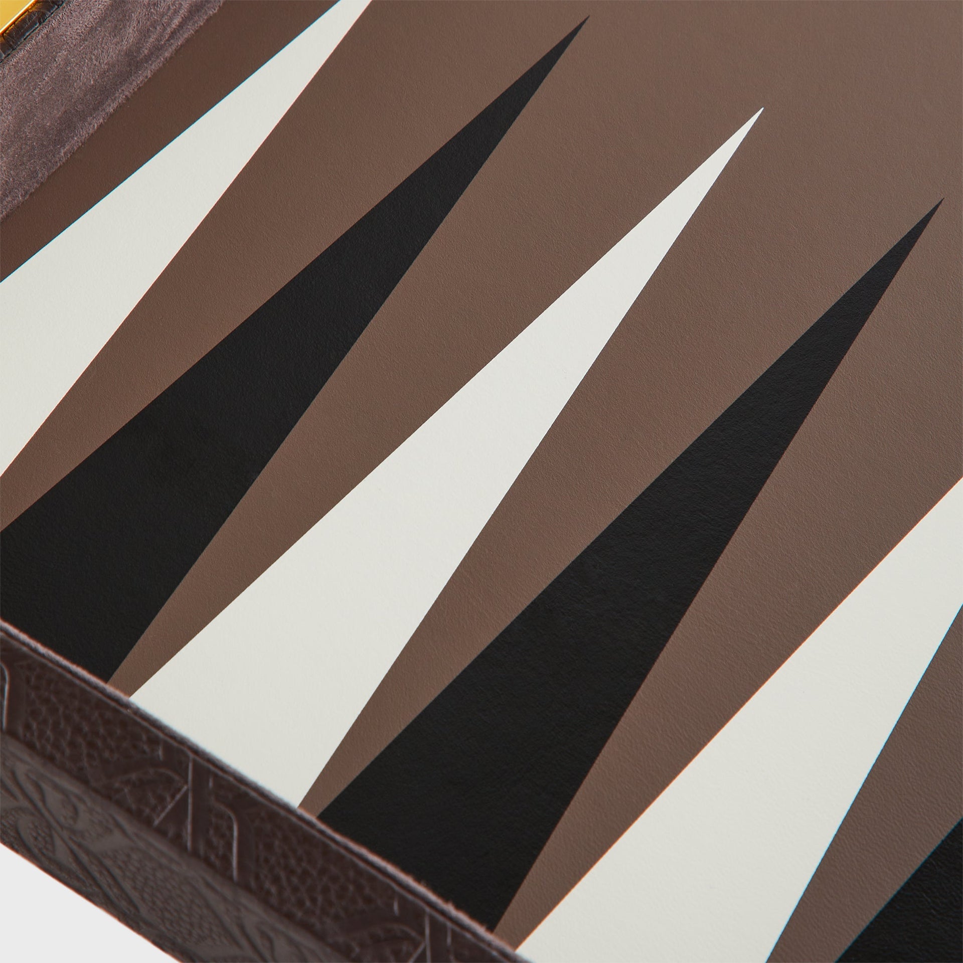 Macro detail of the black, cream, and brown leather triangle points on the backgammon playing surface