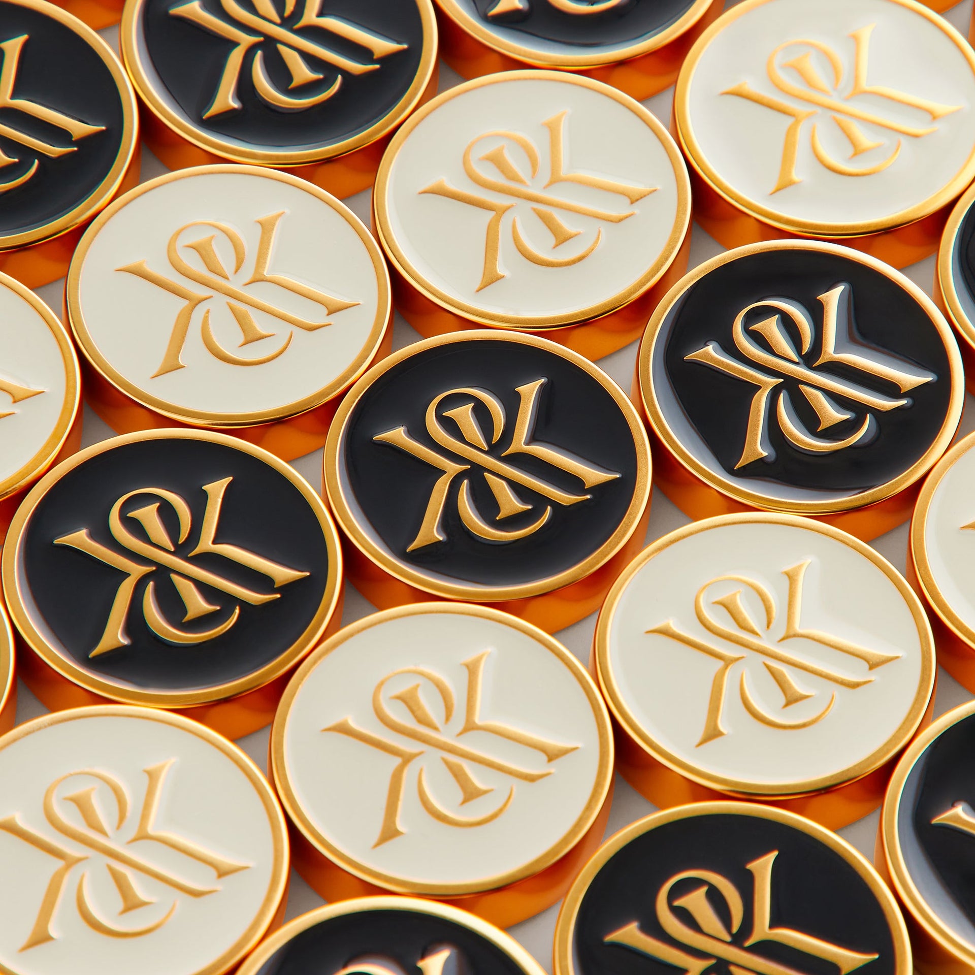 Close-up of black, cream, and gold checker pieces each stamped with the Kith & Kin crest logo
