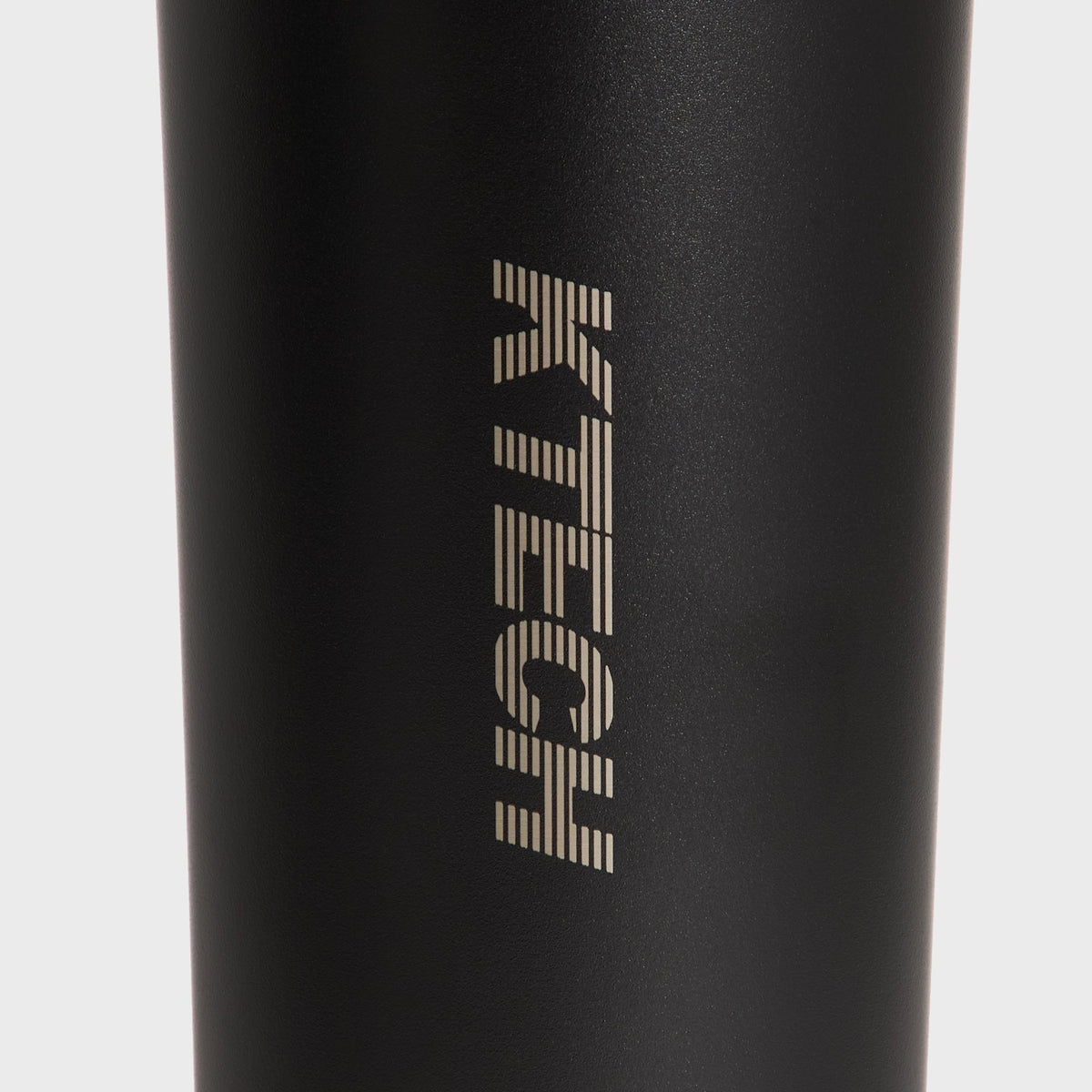 Macro close-up of the KTECH logo etched on the matte black Corkcicle canteen