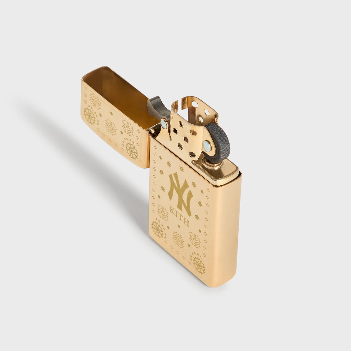 Kith x New York Yankees gold Zippo lighter open at an angle, showing hinge and flint wheel