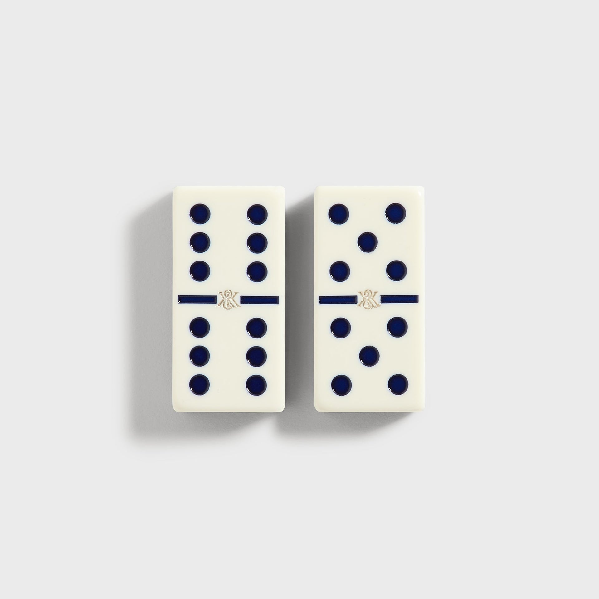 Close-up of two domino tiles face up, showing pip dots and the Kith ampersand emblem at center
