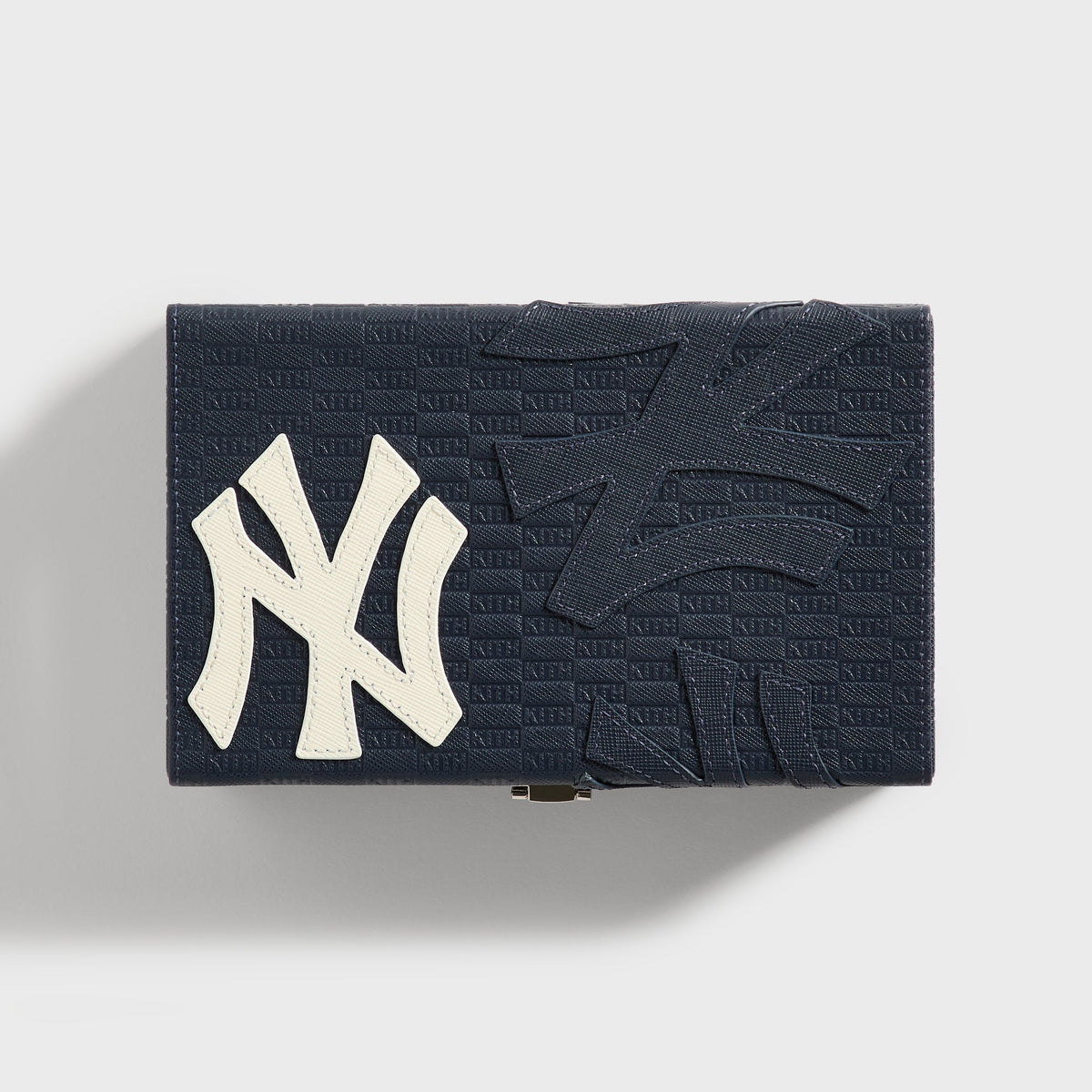 Closed Kith x New York Yankees domino case, top view showing the NY logo patch and brass latch