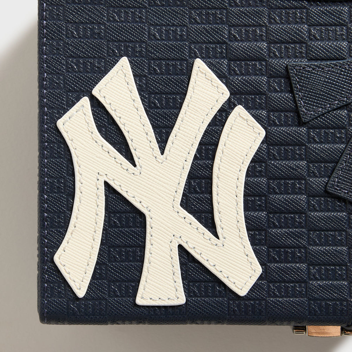 Detail shot of the tone-on-tone stitched Yankees logo debossed into the domino case leather