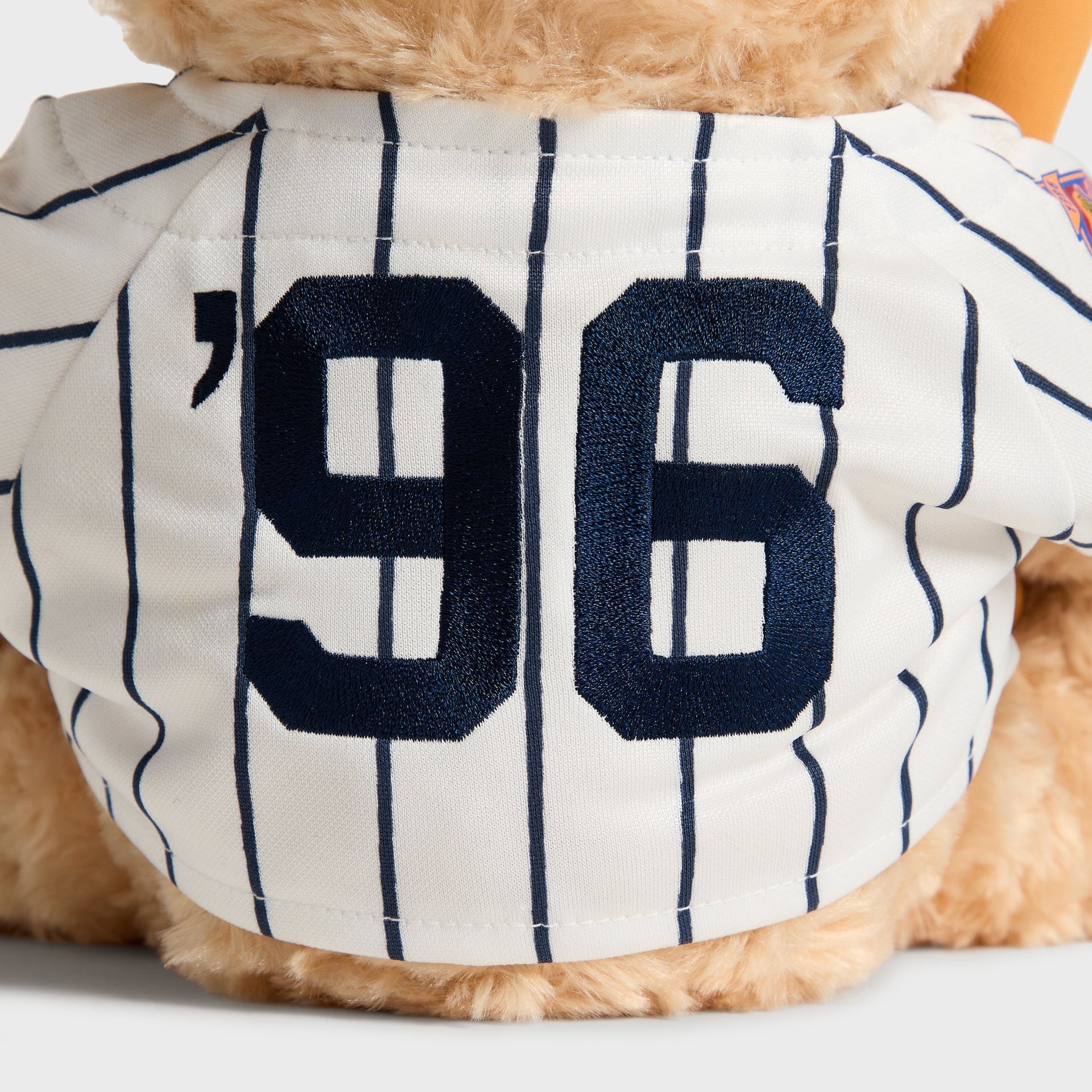 Close-up of embroidered '96 Kith lettering on the jersey back of the Sandrift Teddy Bear