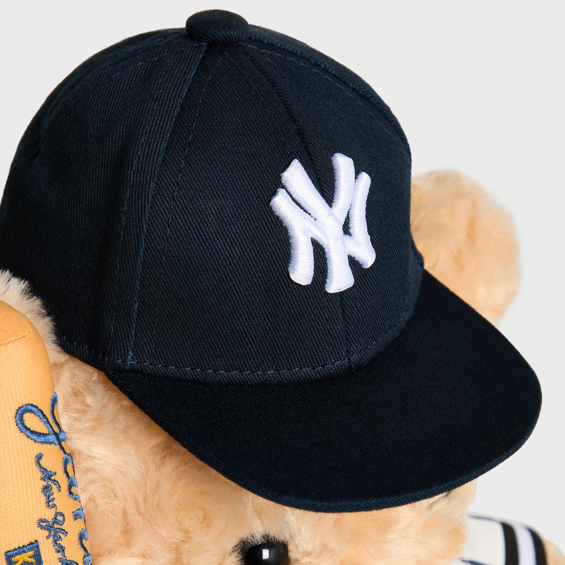 Close-up of NY logo embroidered on the navy cap worn by the Sandrift Teddy Bear
