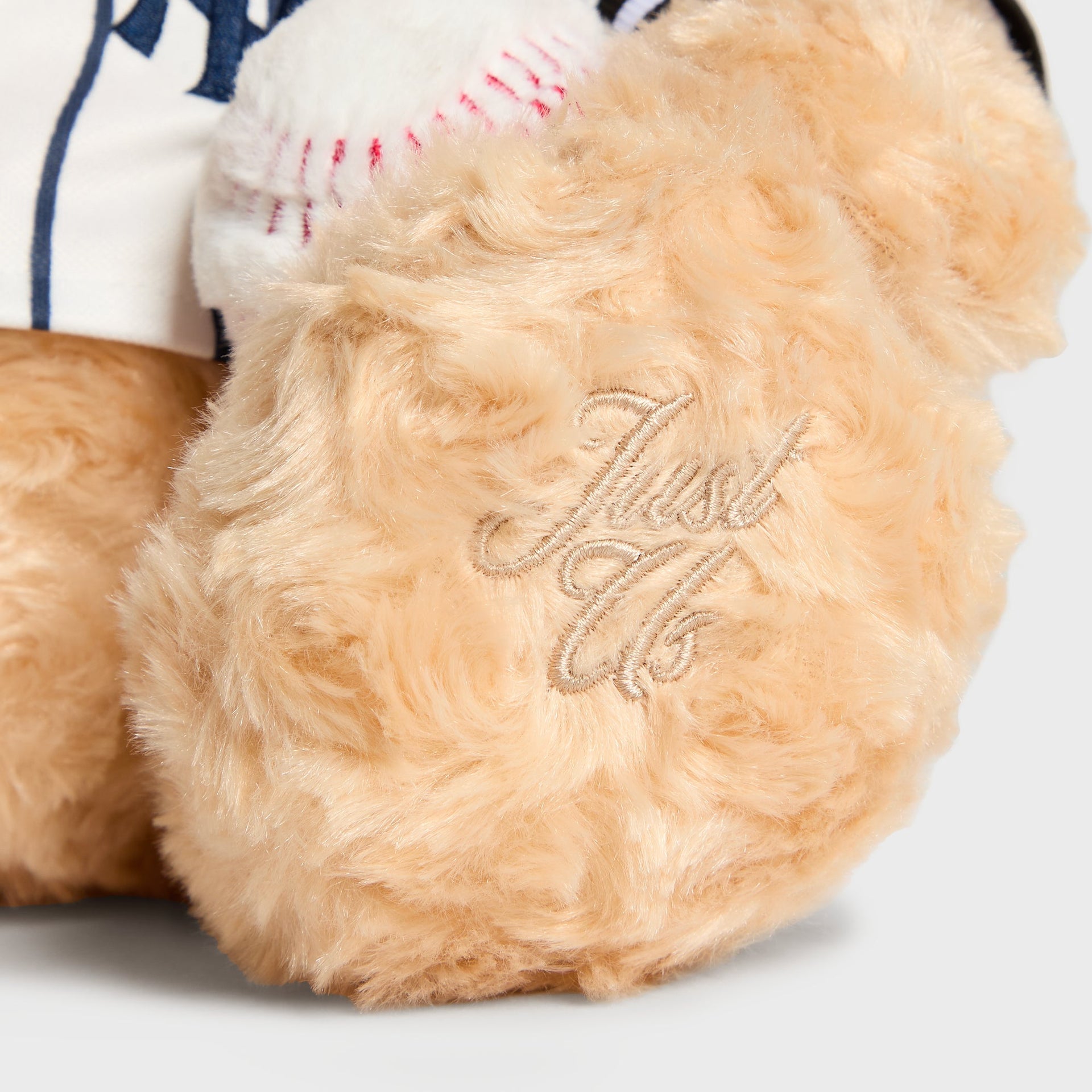 Close-up of Kith signature embroidered on the paw of the Sandrift Teddy Bear