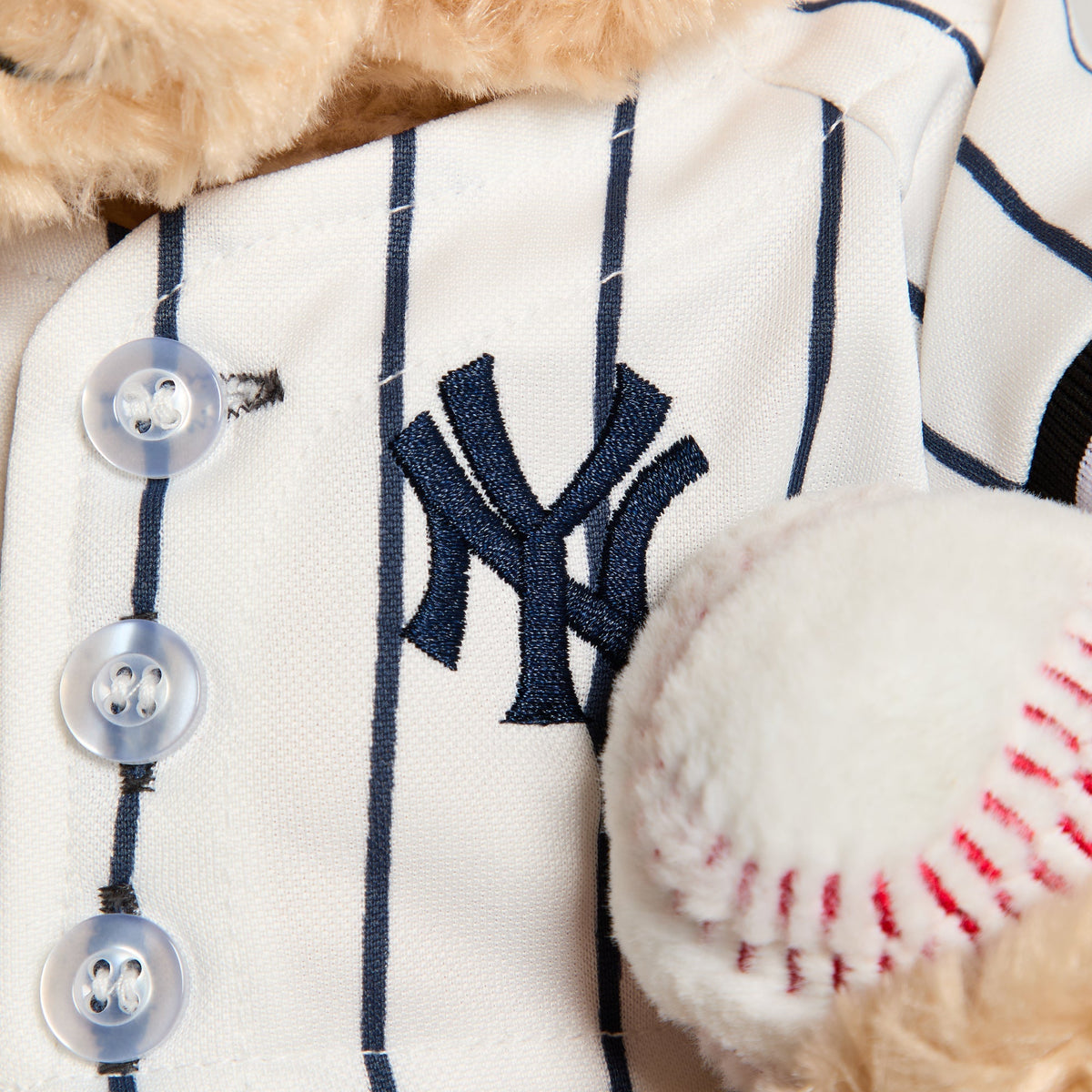 Close-up of embroidered NY logo on pinstripe jersey chest with baseball, Sandrift bear