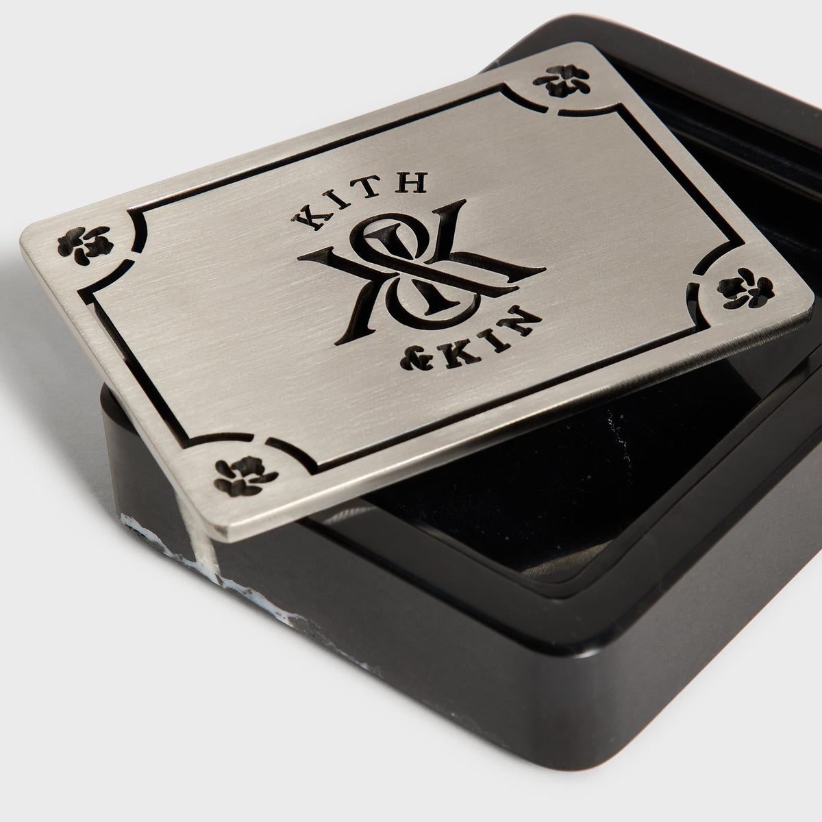 Close-up of brushed metal Kith & Kin lid resting on black marble soap dish
