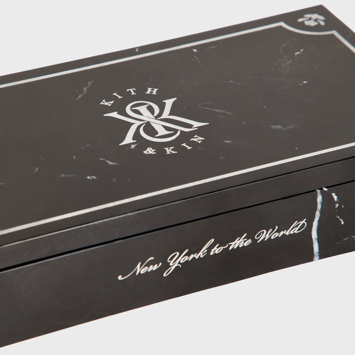 Close-up of Kith & Kin logo and New York to the World script on black marble box