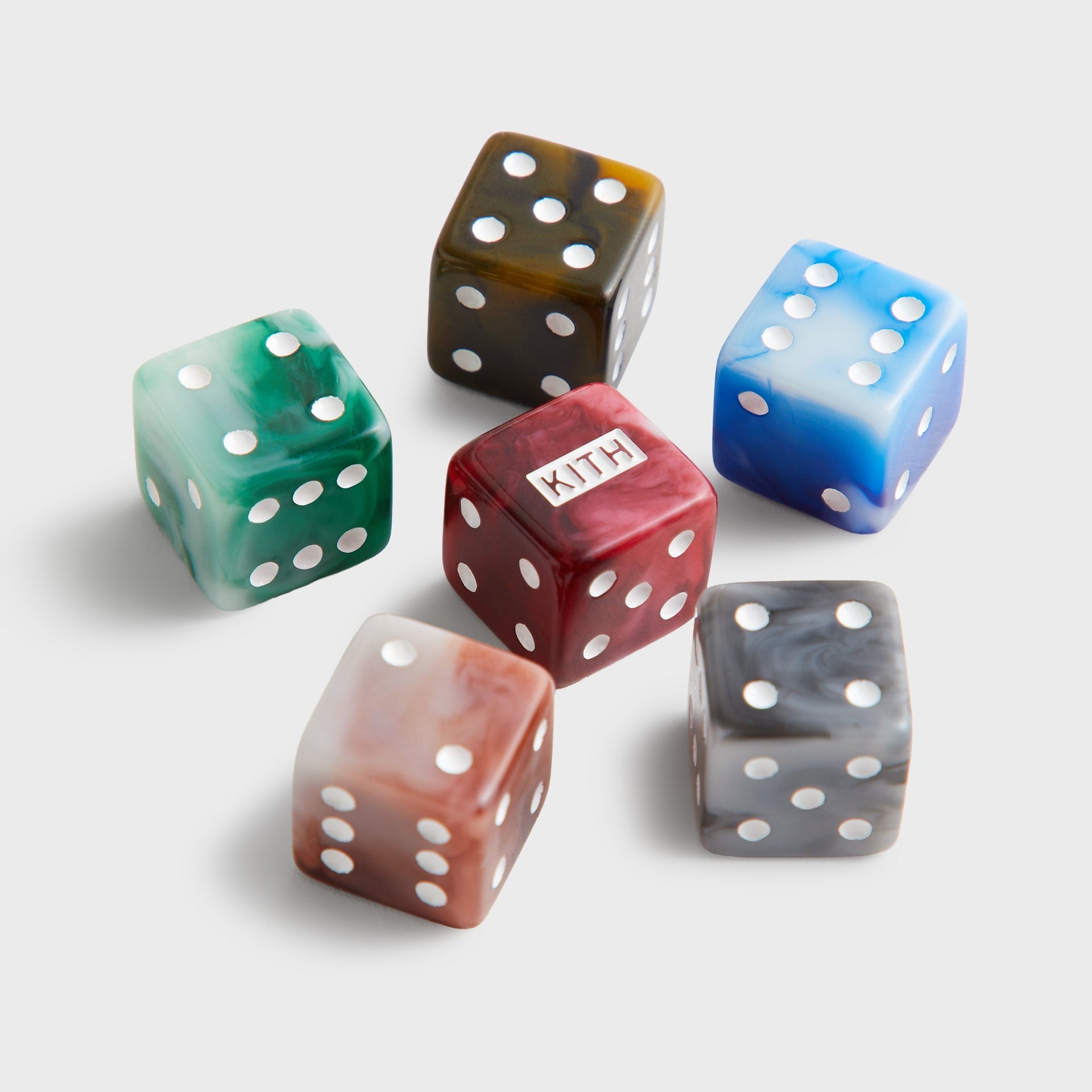 Six marbled acrylic Kith dice in green, amber, blue, red, taupe and grey arranged in a ring on white