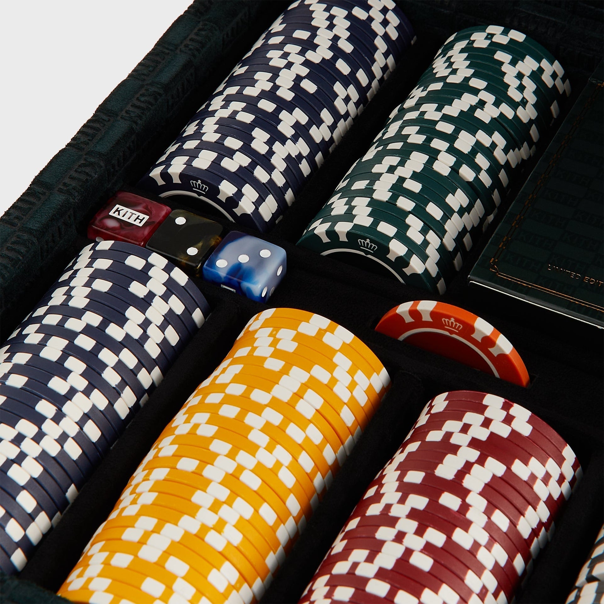 Kith poker chips stacked in navy, yellow and red rows with crown emblem, marbled KITH dice and a Limited Edition card box
