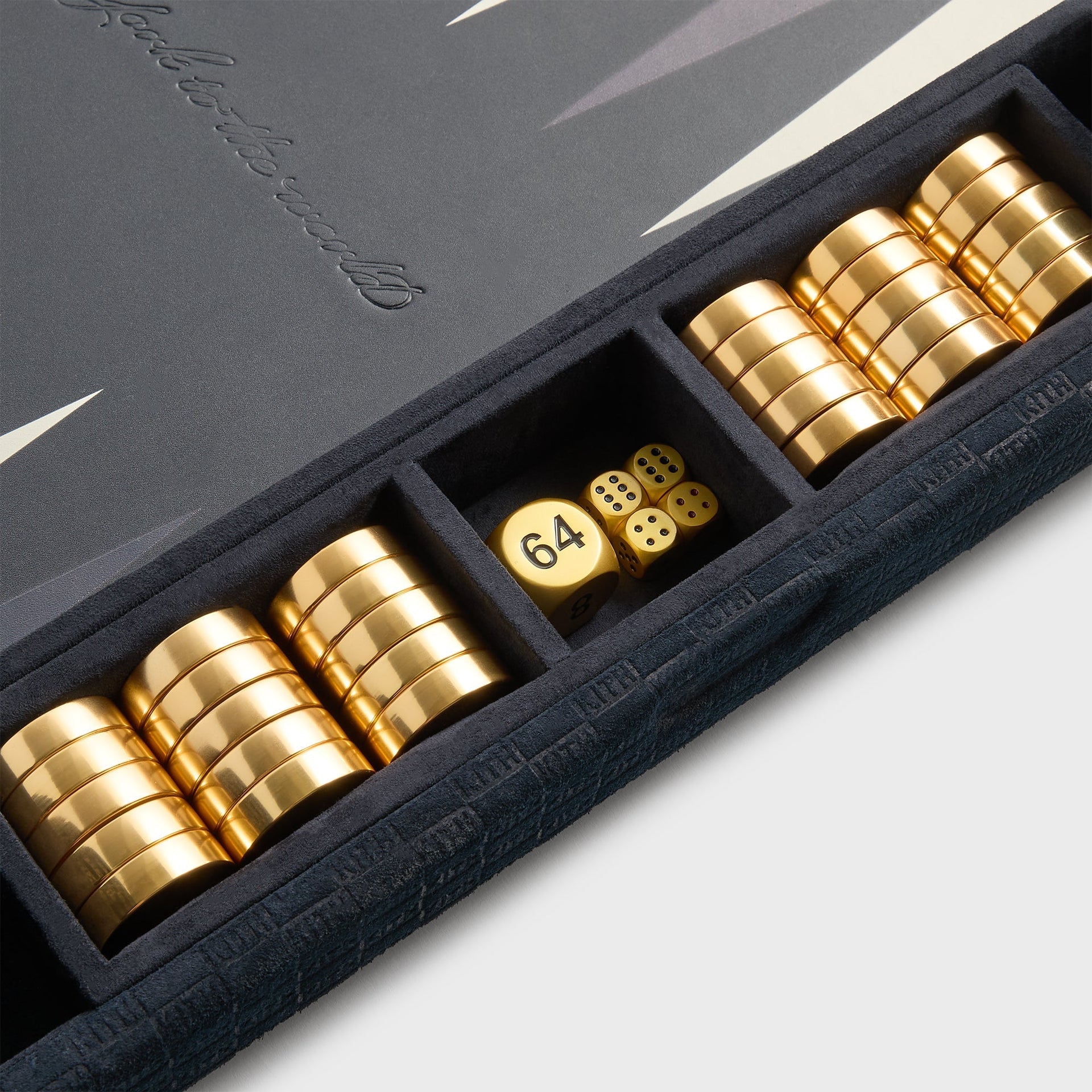 Kith & Kin backgammon board at an angle, gold cylindrical checkers stacked in the ink suede tray beside gold dice and doubling cube
