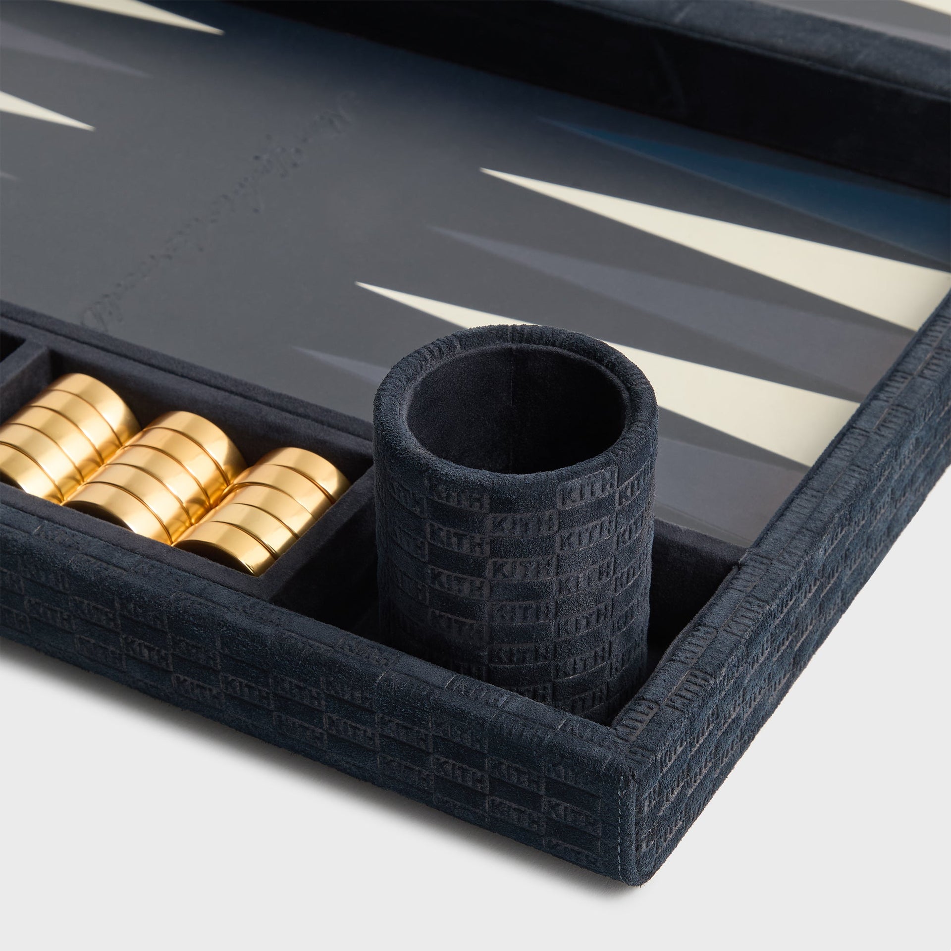 Ink suede KITH-monogram dice cup and stacked gold checkers set into the tray corner of the Kith backgammon board