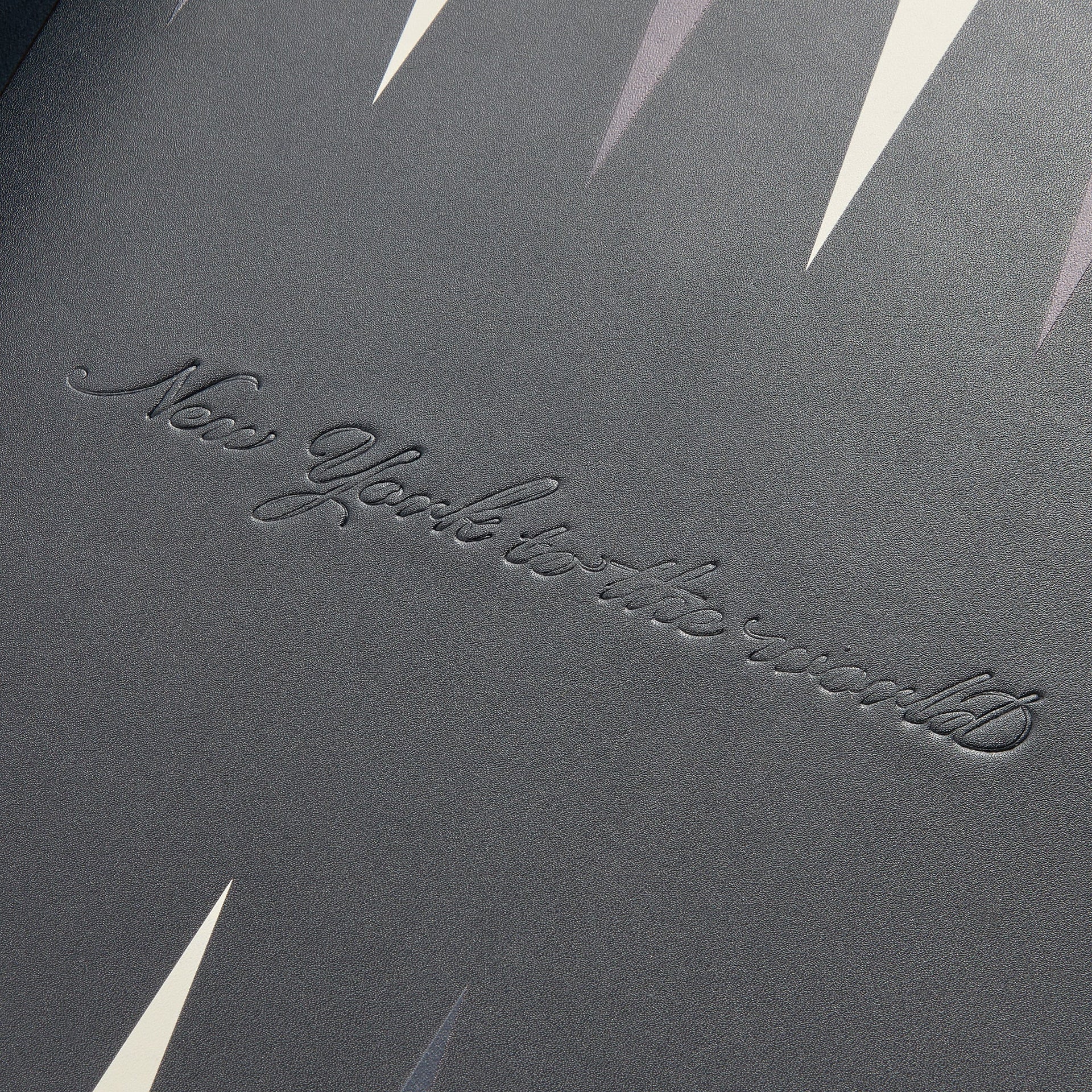 New York to the World script embossed on the grey backgammon playing surface with cream and navy points, close-up