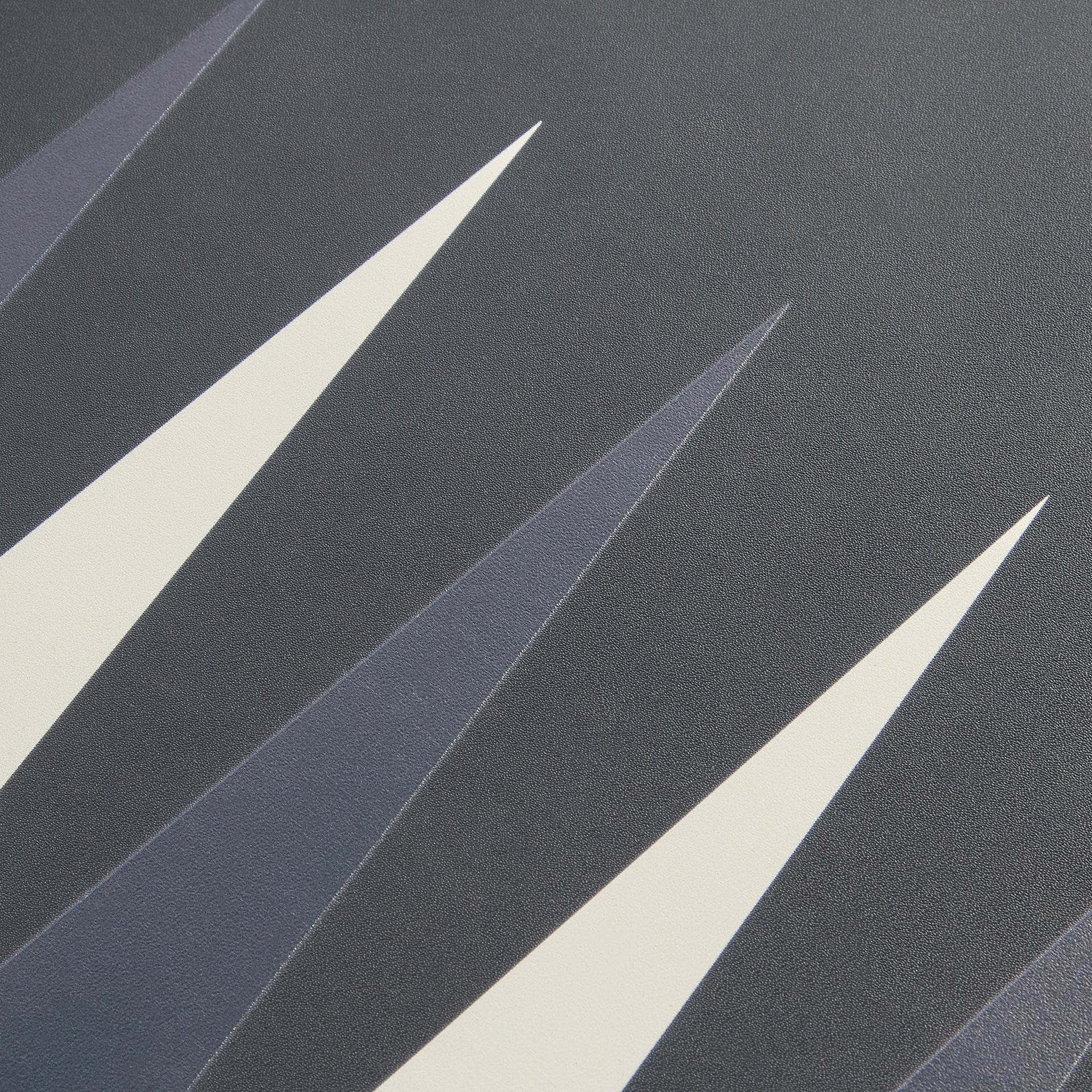 Macro of the Kith backgammon points, cream and navy triangles across the textured grey suede playing surface