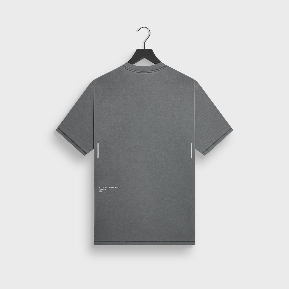 Kith Garment-Dyed Heathrow Tee in shadow grey, flat lay back view with Kith Technology wordmark and reflective sleeve bars