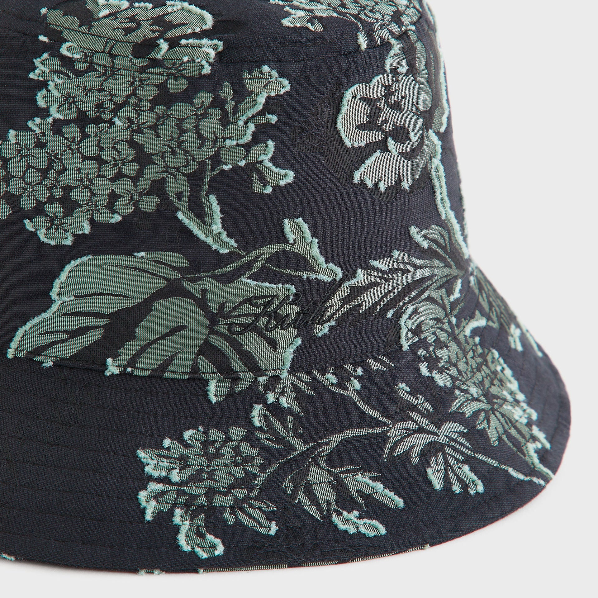 Close-up detail of the black and sage green floral clip jacquard fabric on the Kith for Needles Dawson bucket hat