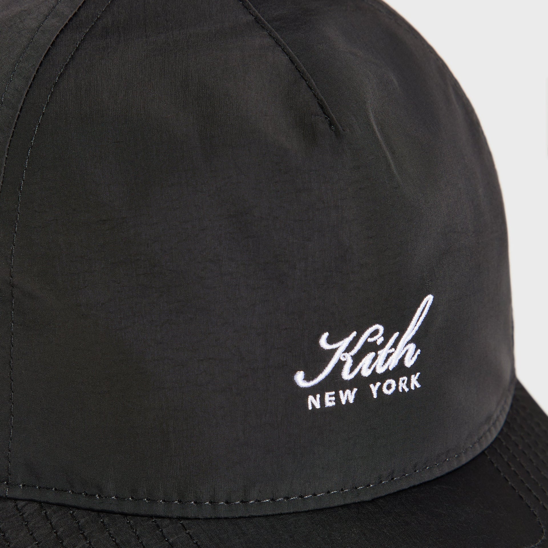 Close-up of the embroidered Kith New York script logo on the wrinkle nylon Bay snapback in black