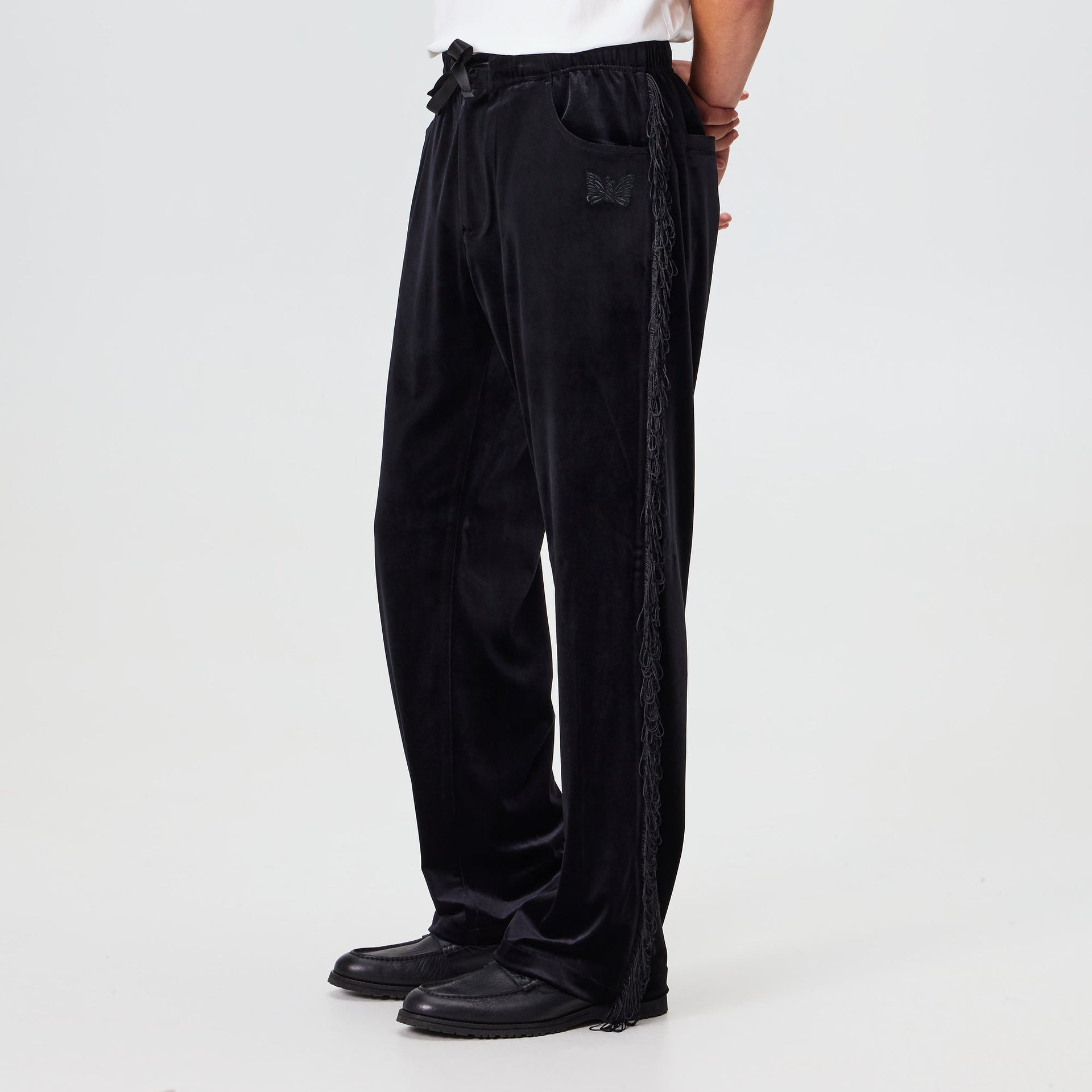 Man wearing the Kith for Needles Ronan fringe pant in black velour, side view