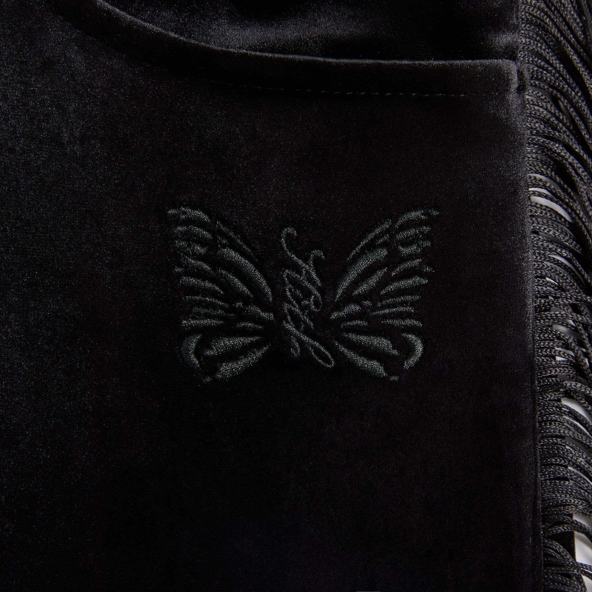 Close-up of the tonal embroidered butterfly on the back pocket of the Ronan fringe pant