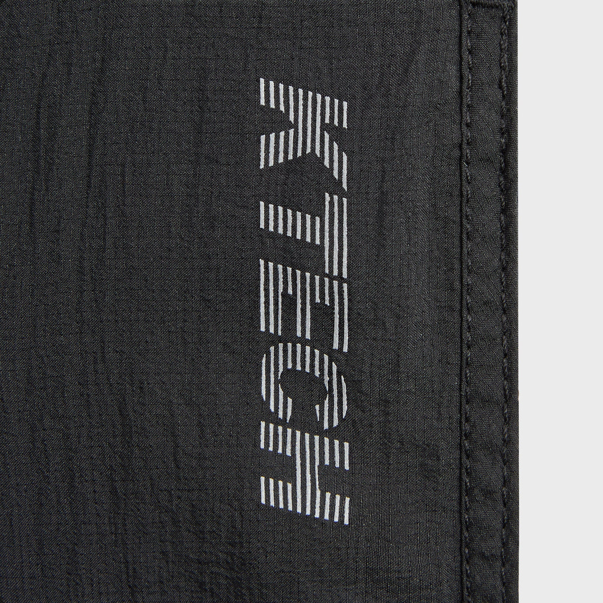 Man modeling Kith Ceres 3-inch Short in black, side view showing dolphin hem slit
