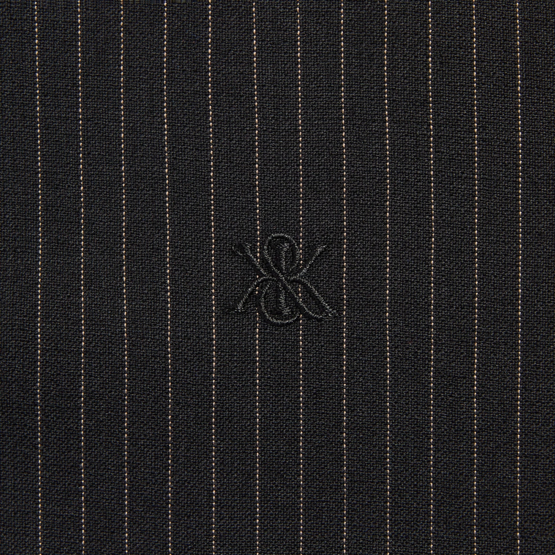 Close-up of the embroidered ampersand K logo on the Kith Pinstripe Rui track jacket