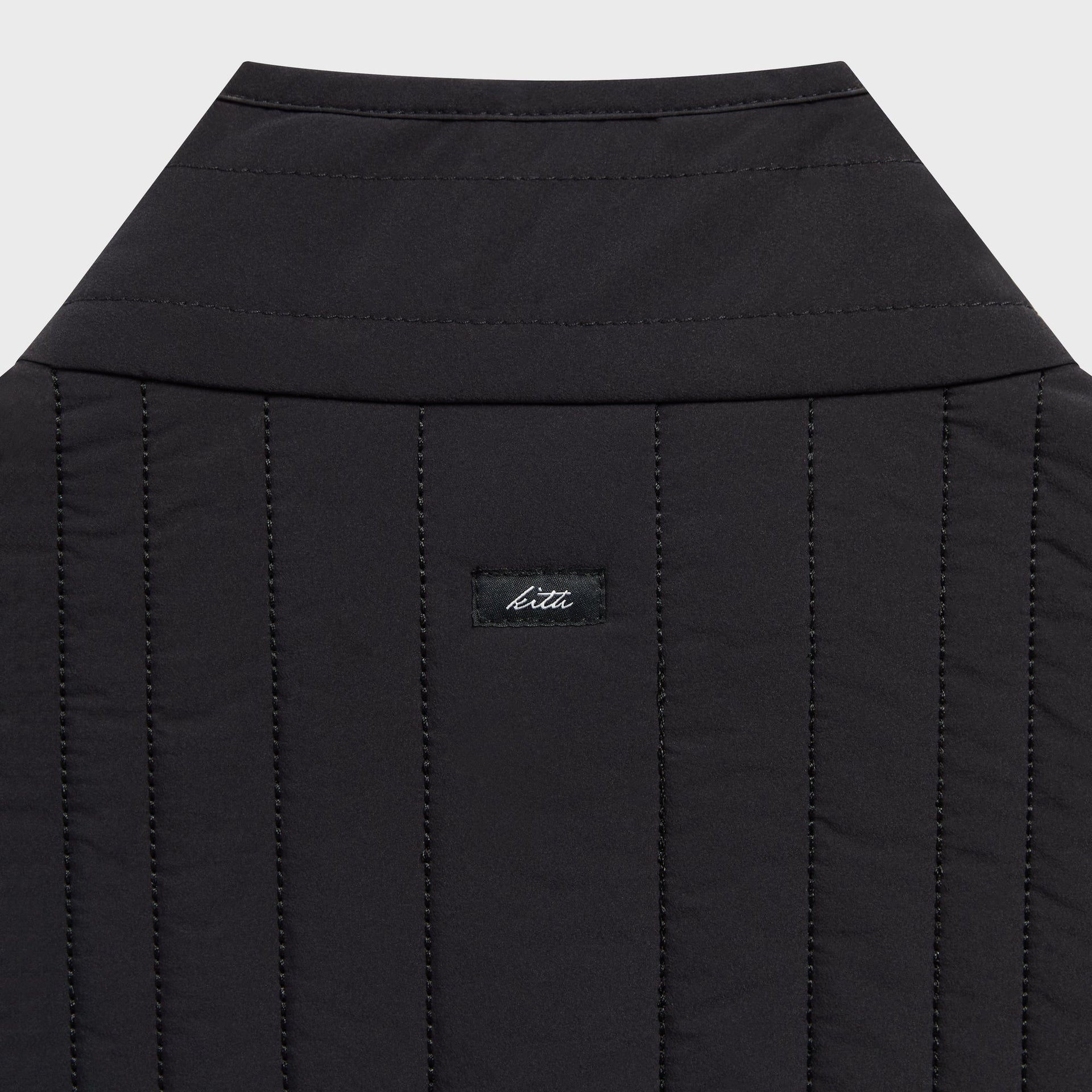 Close-up of the woven logo patch on the back yoke of the Kith Quilted Nylon Lorenzo vest