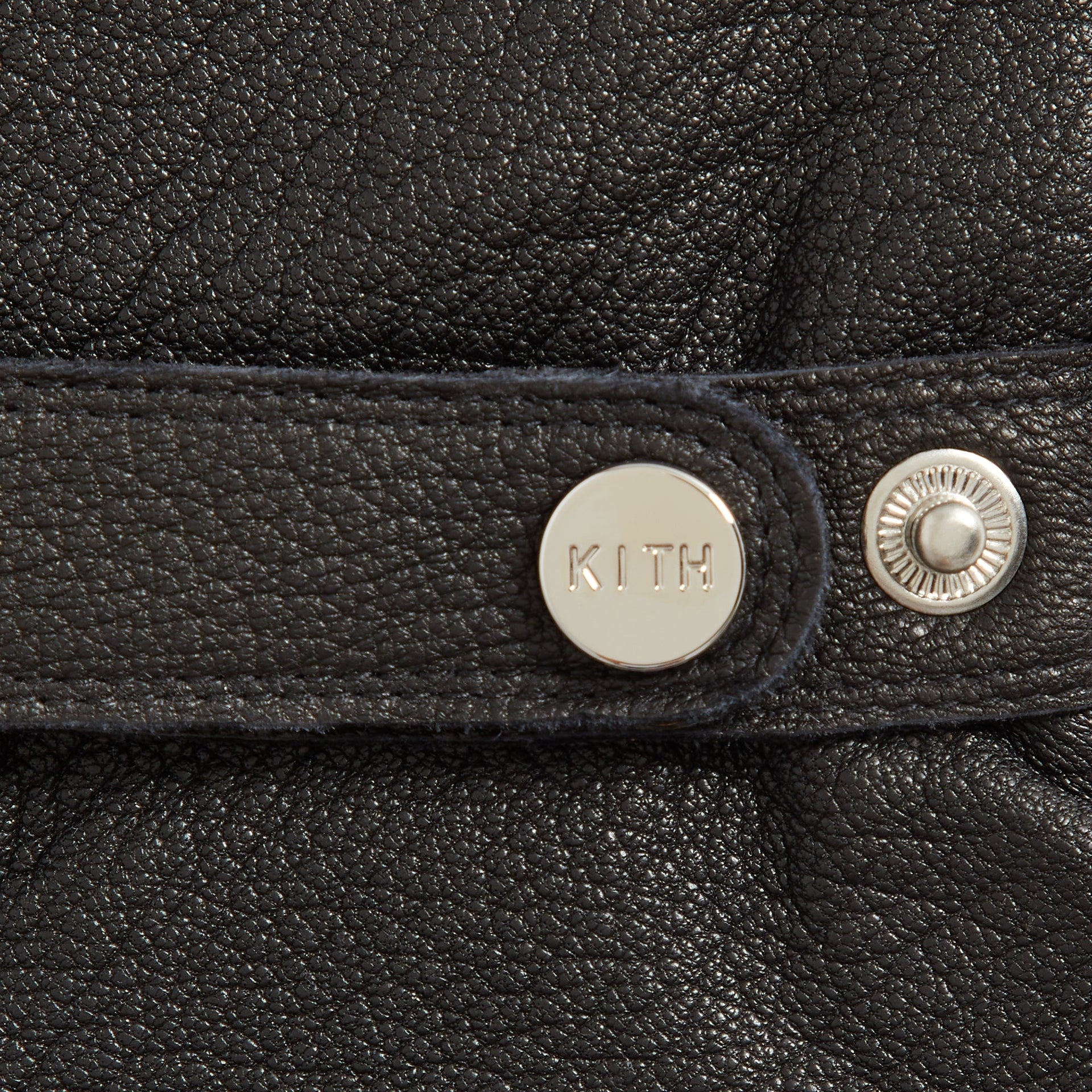 Close-up detail of KITH branded snap button and adjustable strap on Manhattan leather gloves in Black