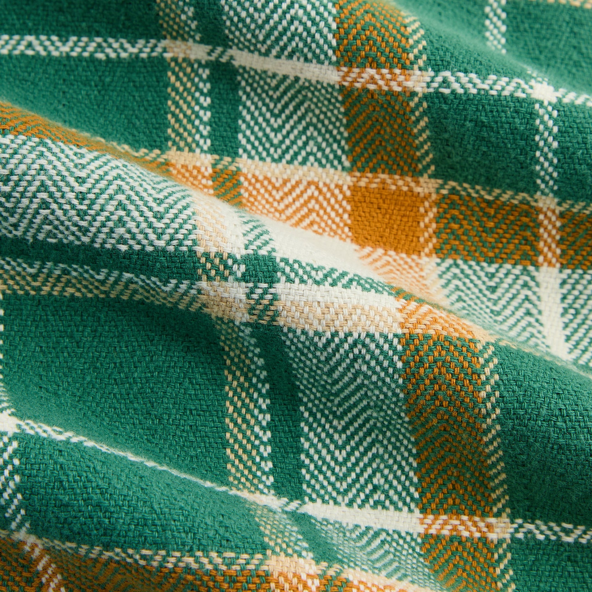Close-up of the green, orange and cream plaid flannel weave on the Kith Henson buttondown shirt