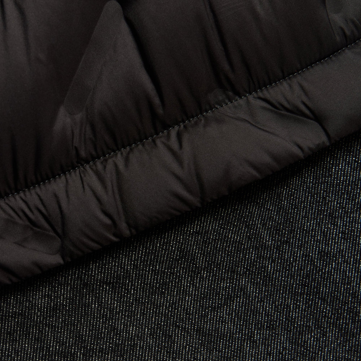Close-up of the quilted nylon and washed denim hem transition on the Gertie shirt