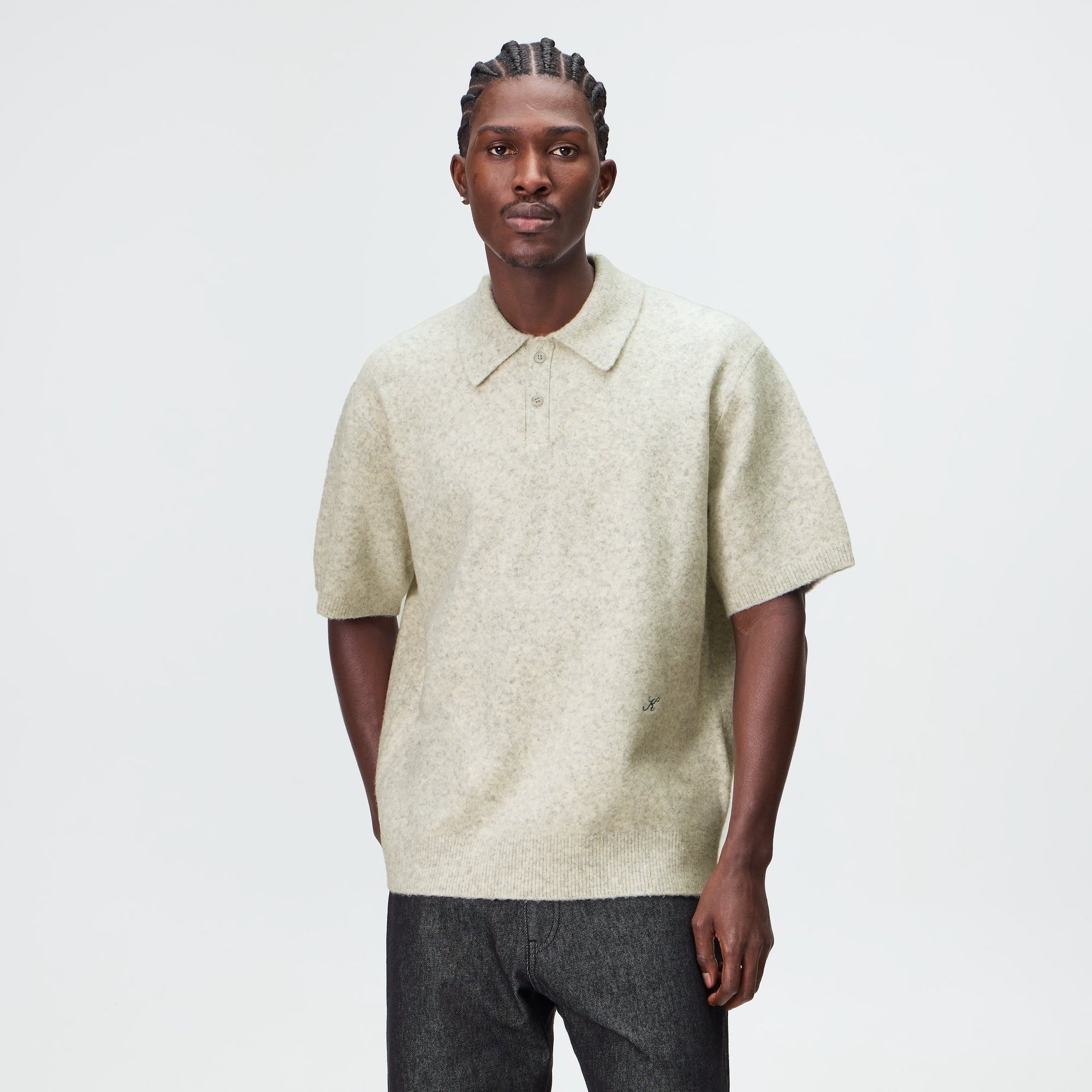 Man wearing the Kith Boucle Tobey polo in light heather grey with grey trousers