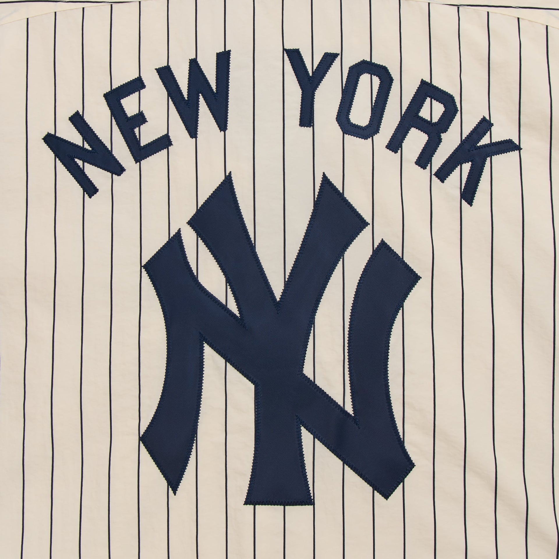 Close-up of New York and NY logo appliqué on the back of the cream Nylon Raffi pullover