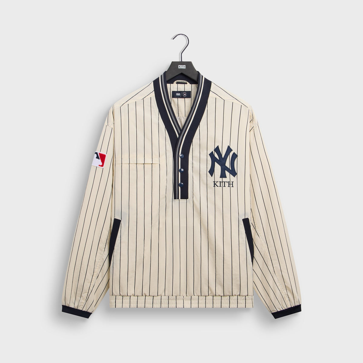 Cream Sandrift Kith for New York Yankees Nylon Raffi pullover with navy pinstripes and NY Kith logo, front flat lay