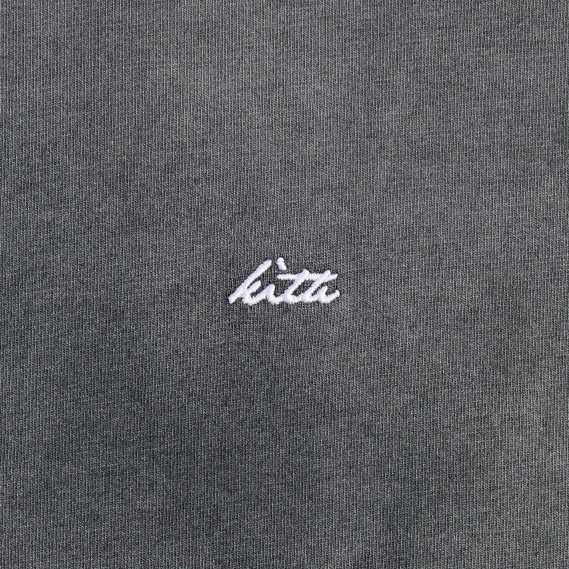 Close-up of the embroidered Kith script logo on the Jones tee in faded black